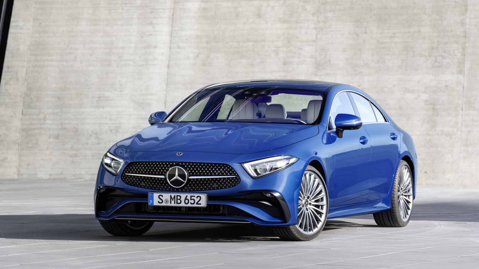 Синий автомобиль Mercedes-Benz CLS 350 AMG Line 2021 года на фоне серой стены