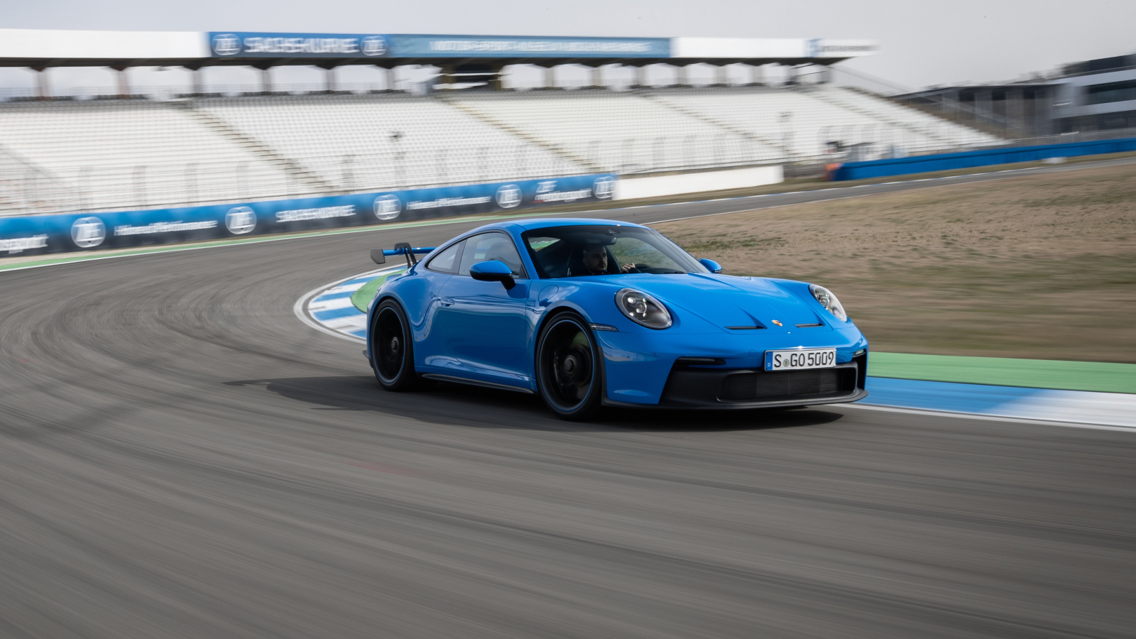 Голубой автомобиль Porsche 911 GT3 2021 года на стадионе