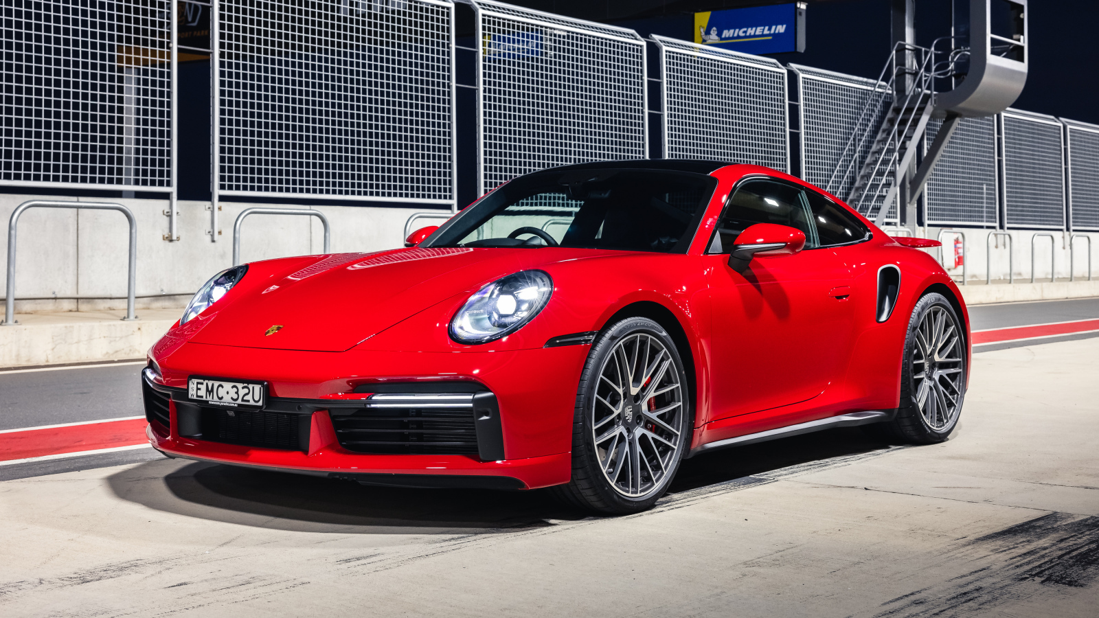 Красный автомобиль Porsche 911 Turbo 2021 года на стадионе