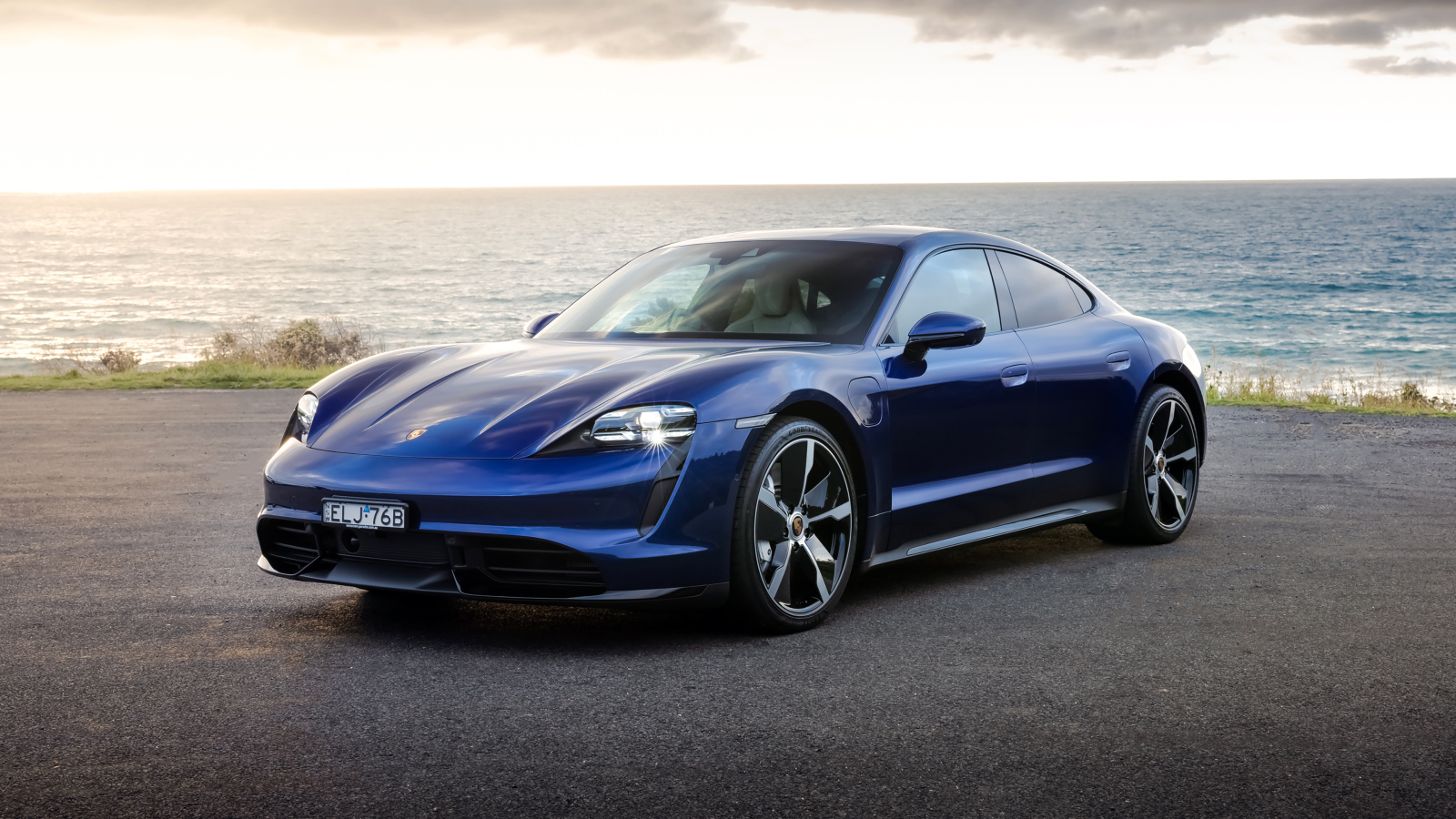 Синий автомобиль Porsche Taycan Turbo у моря
