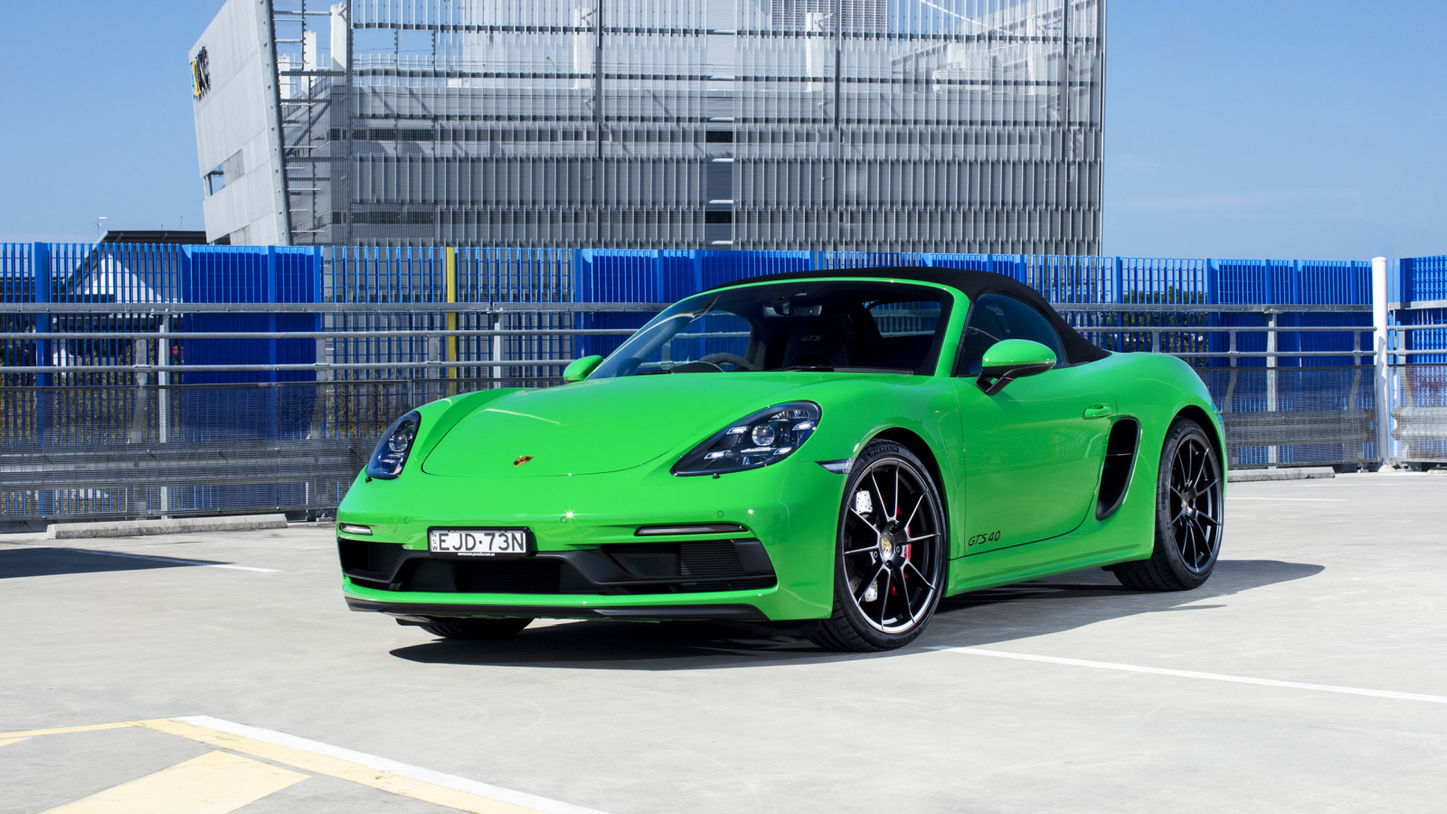 Зеленый автомобиль Porsche 718 Boxster GTS у здания 