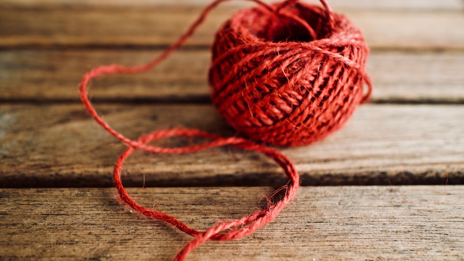 Клубок красной пряжи на деревянном столе 