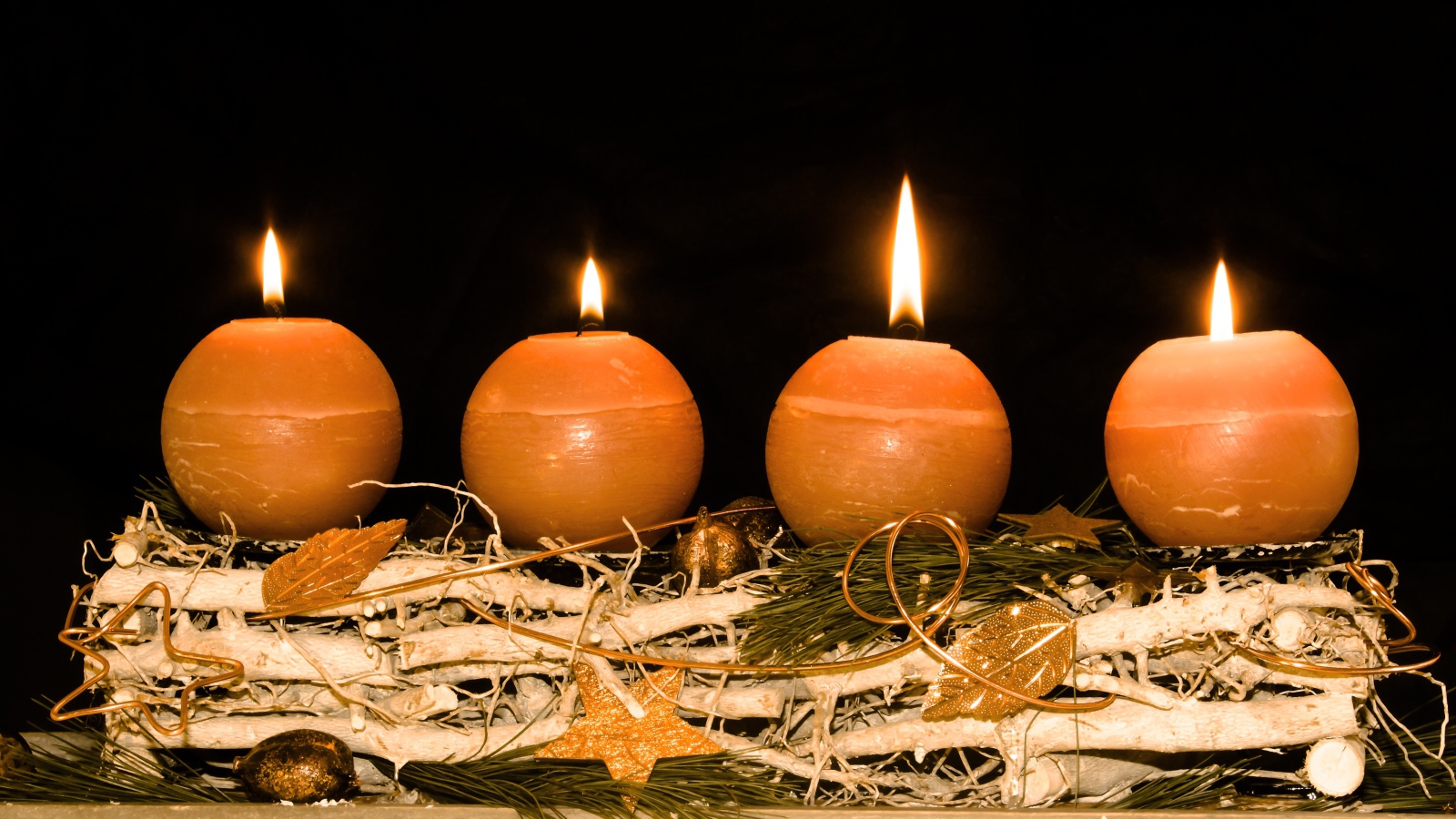 Четыре круглые зажженные свечи на черном фоне