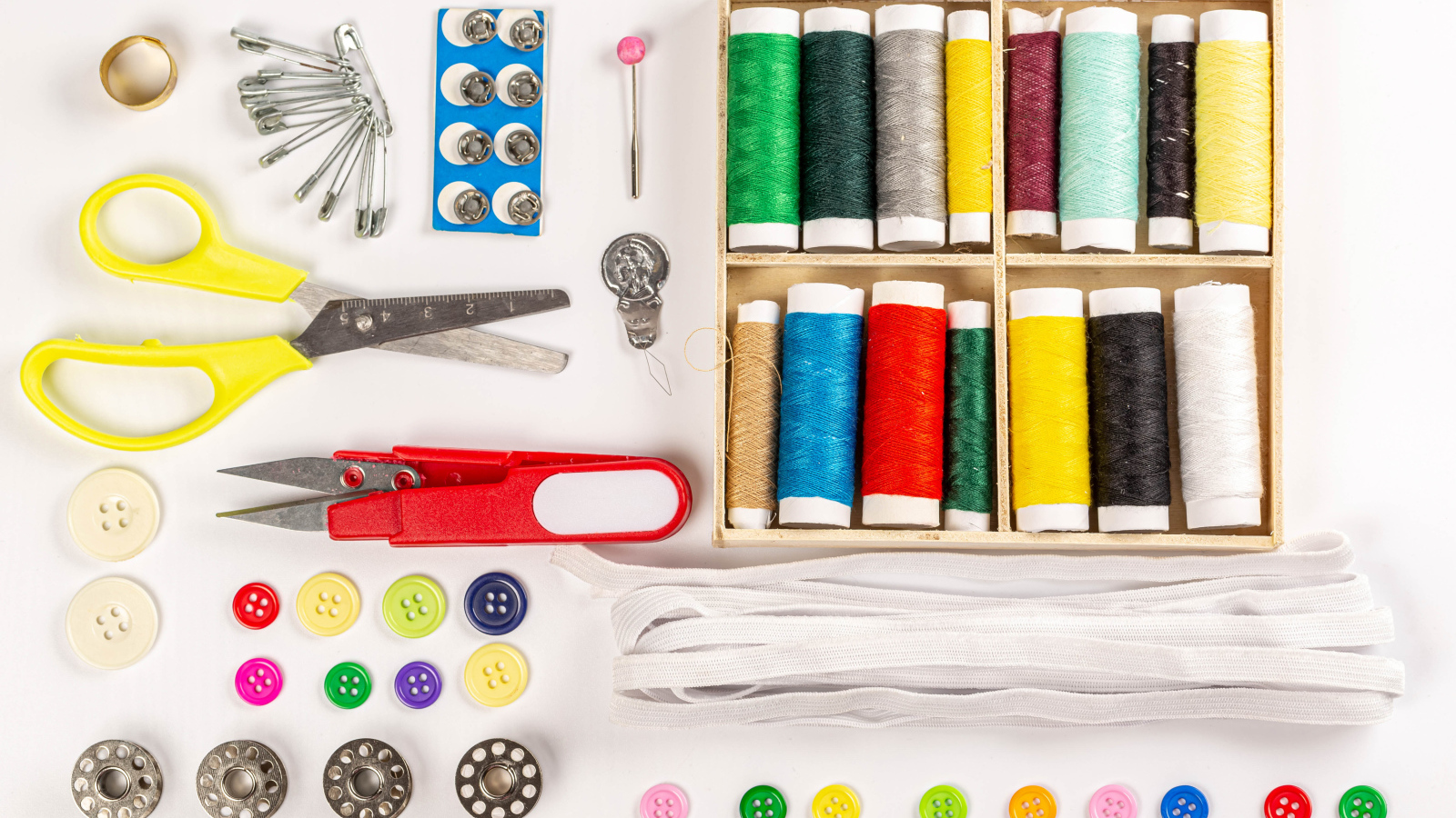 Разноцветые нитки и предметы для шитья на белом фоне 