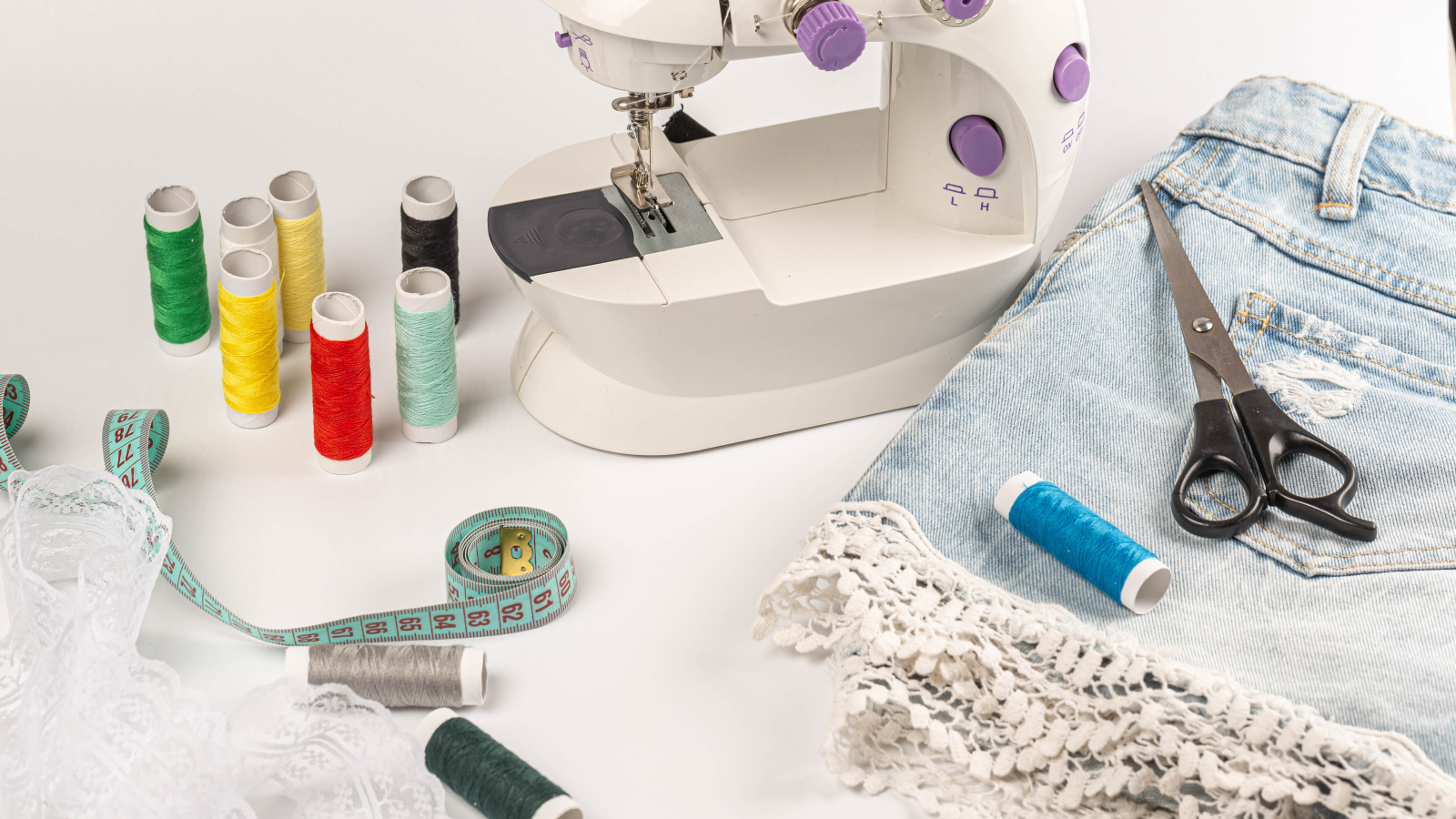 Швейная машинка,юбка и нитки на белом фоне 