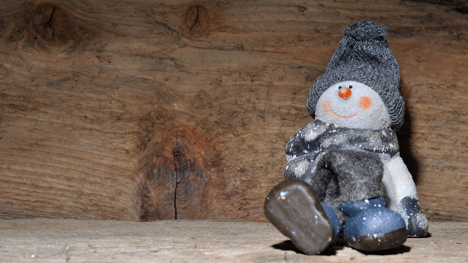 Фигурка снеговик у деревянной стены