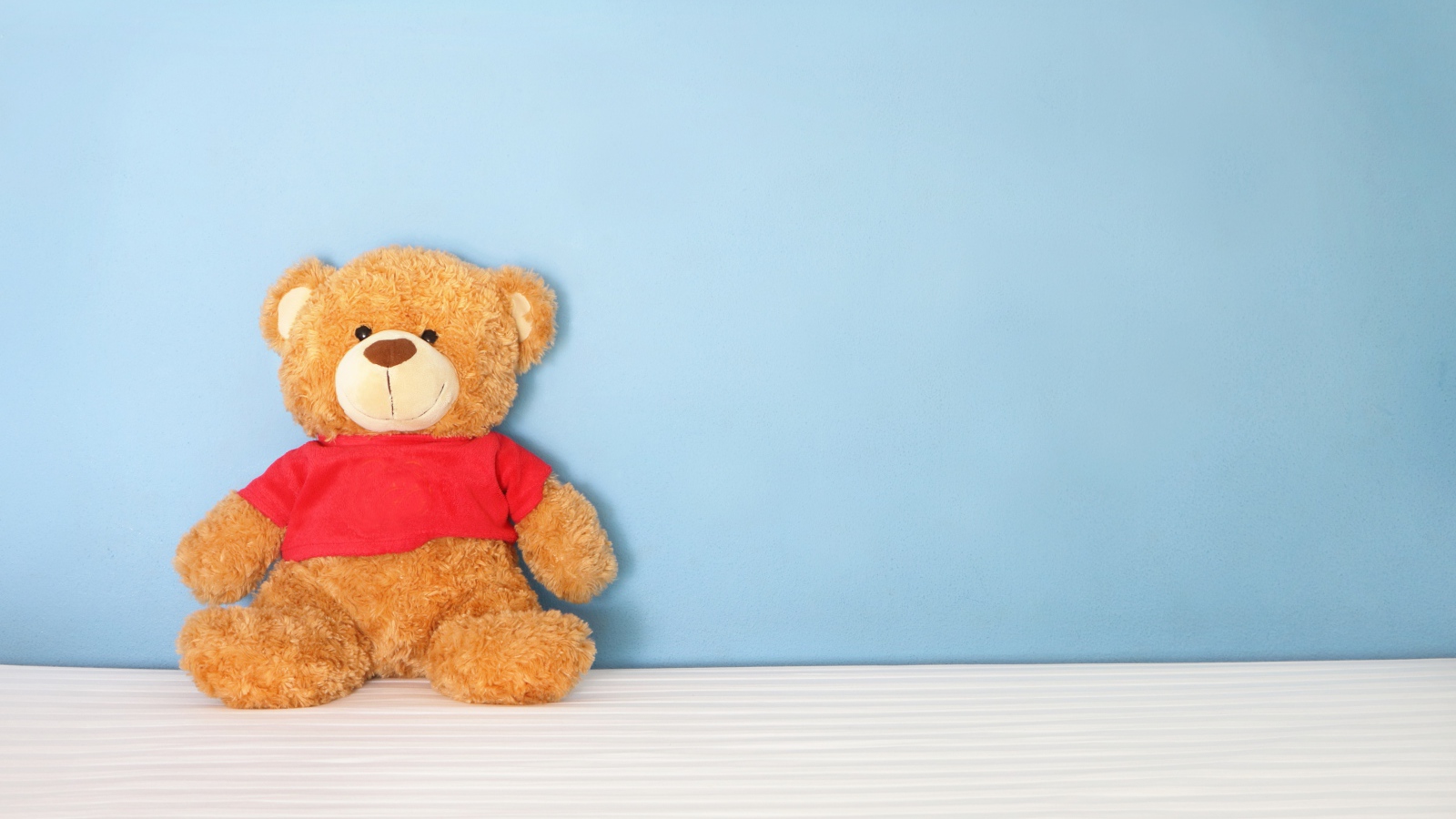 Плюшевый мишка на фоне голубой стены