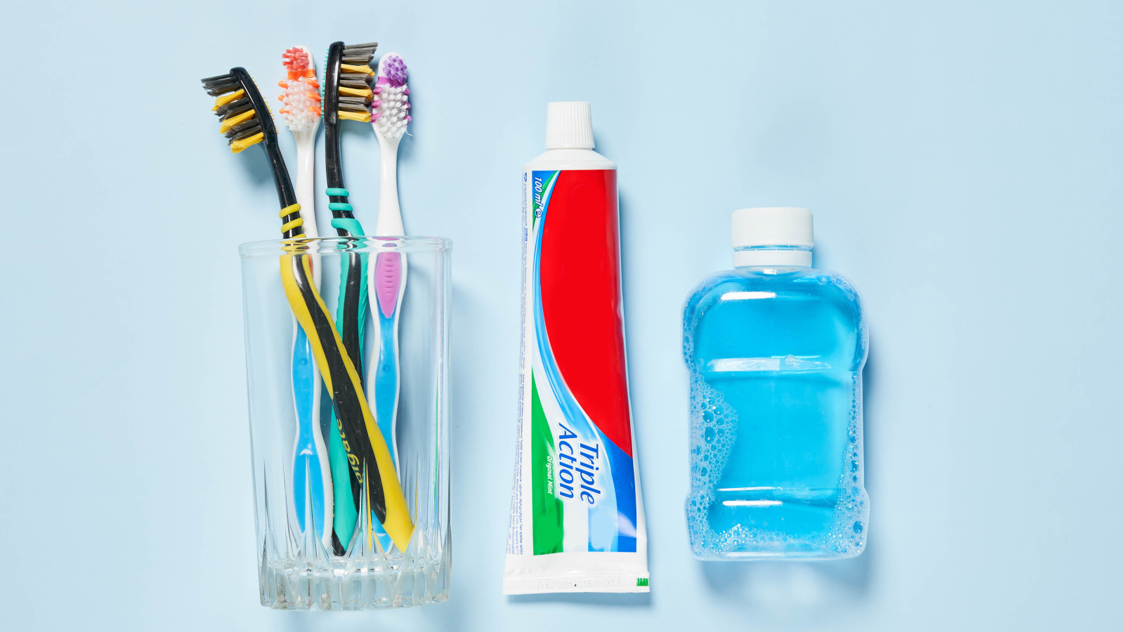 Зубная паста с щетками и ополаскивателем на сером фоне 