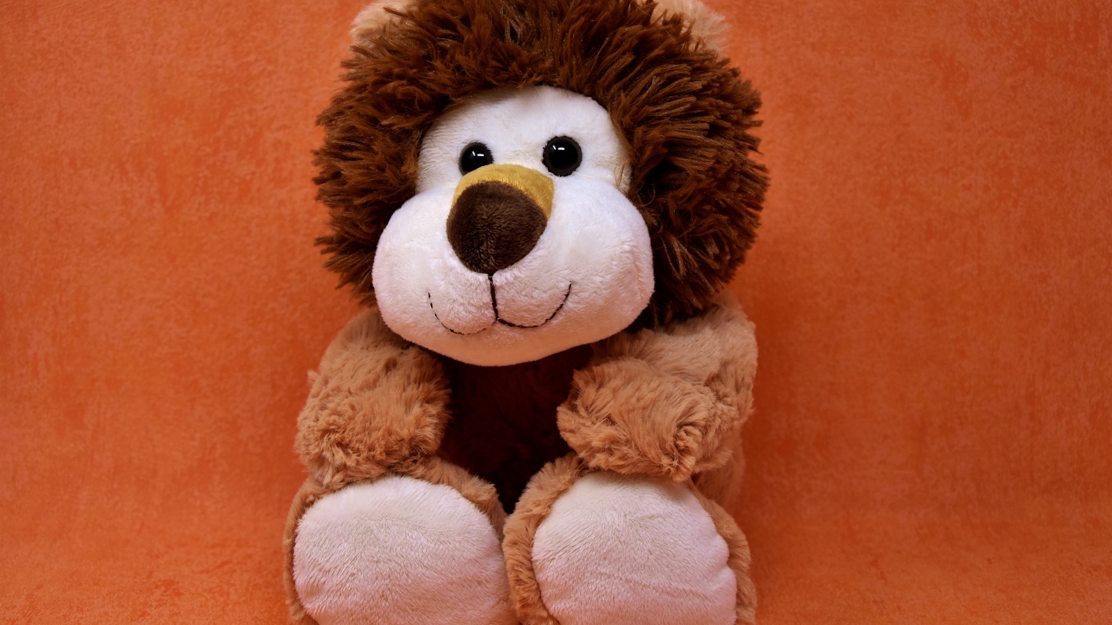 Игрушечный лев на фоне стены