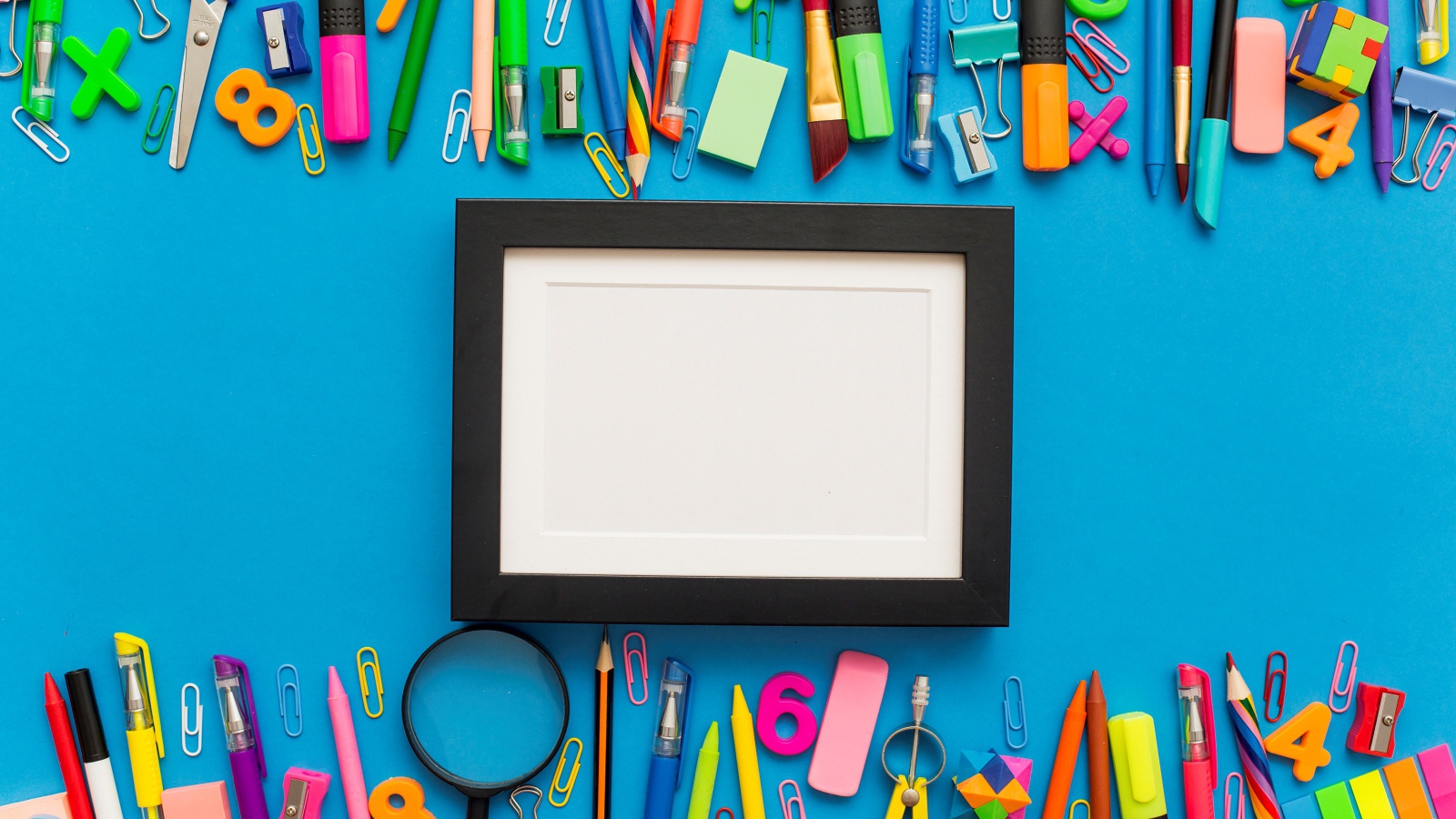 Белая рамка с разноцветными канцелярскими предметами на голубом фоне