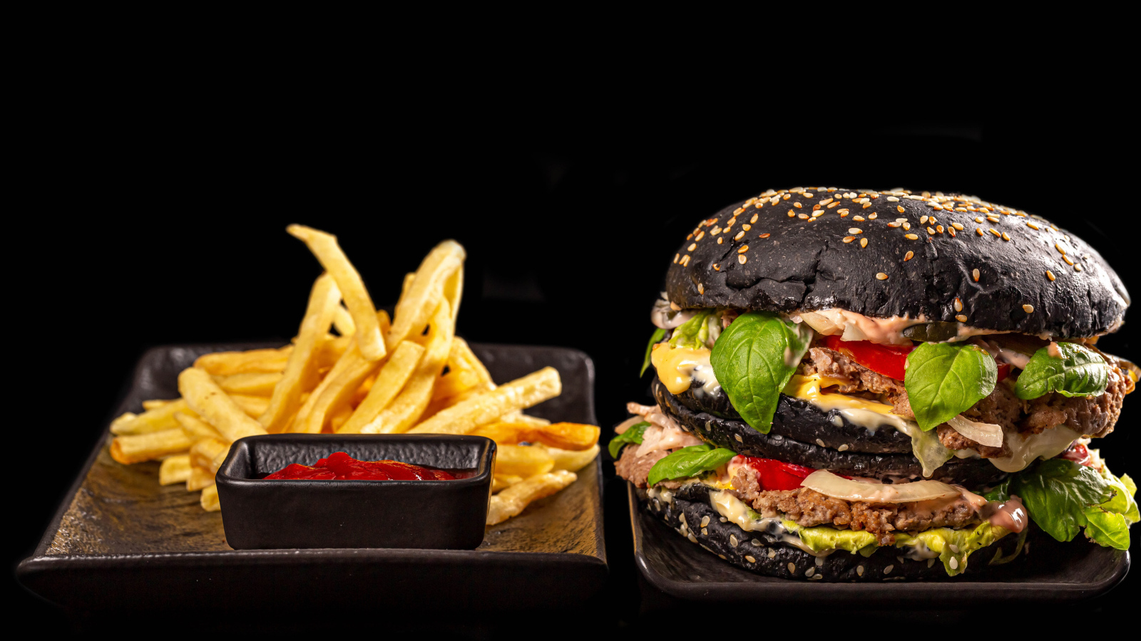 Большой черный гамбургер с картофелем фри и кетчупом 