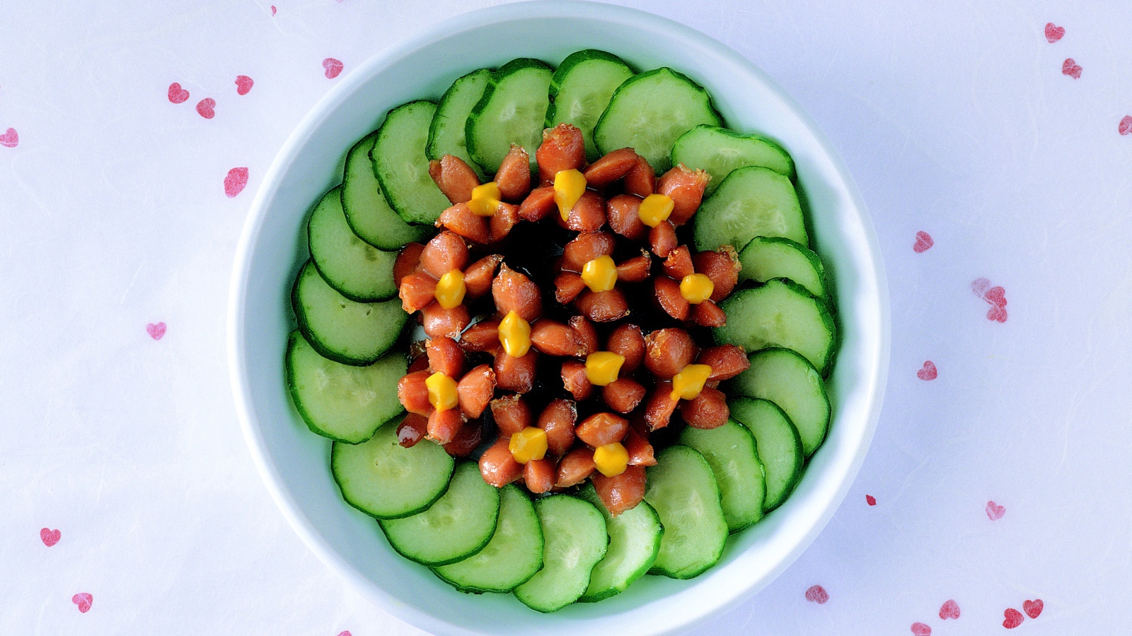 Огурцы с сосисками в тарелке на столе