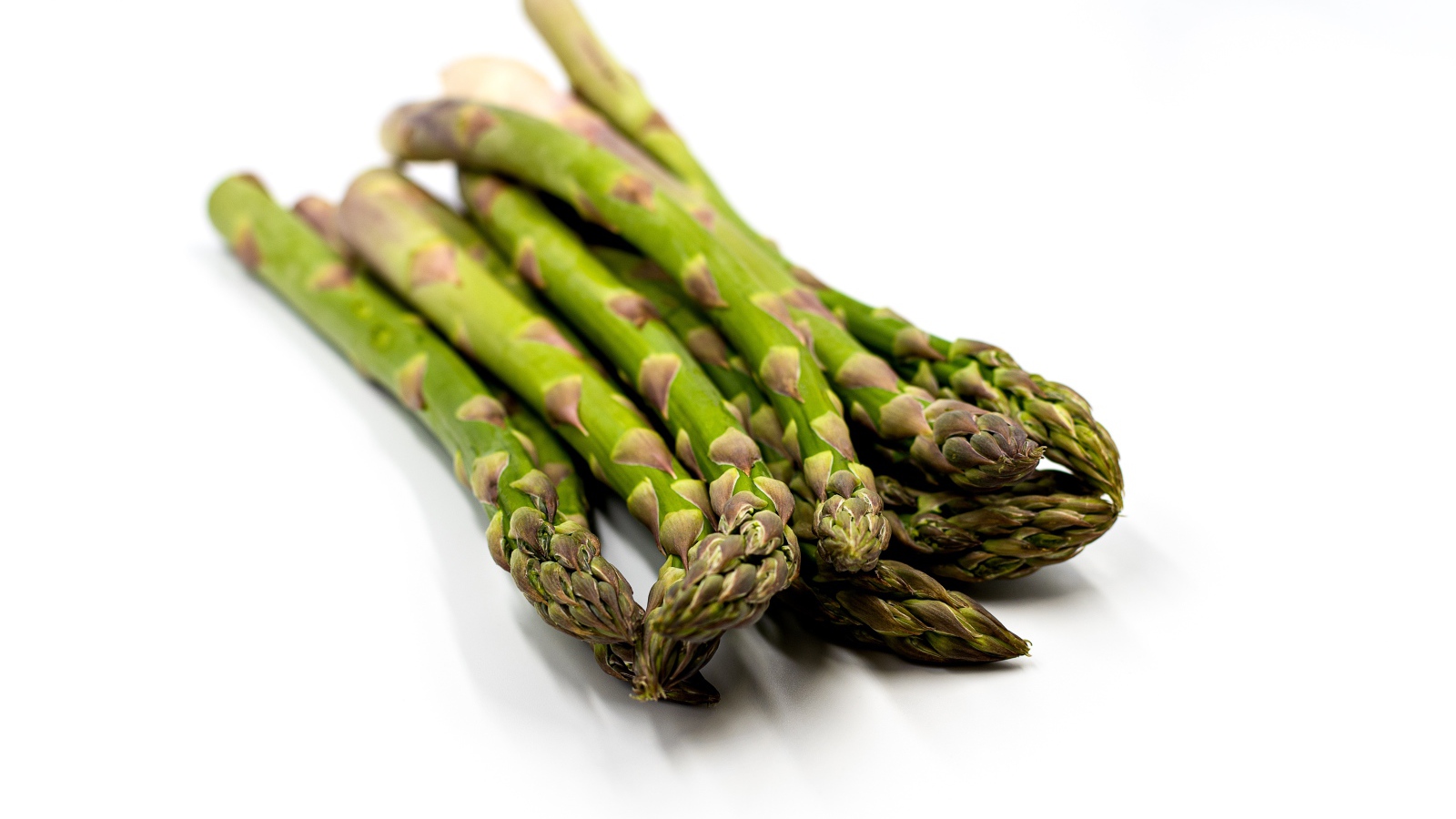 Свежая зеленая спаржа на белом столе