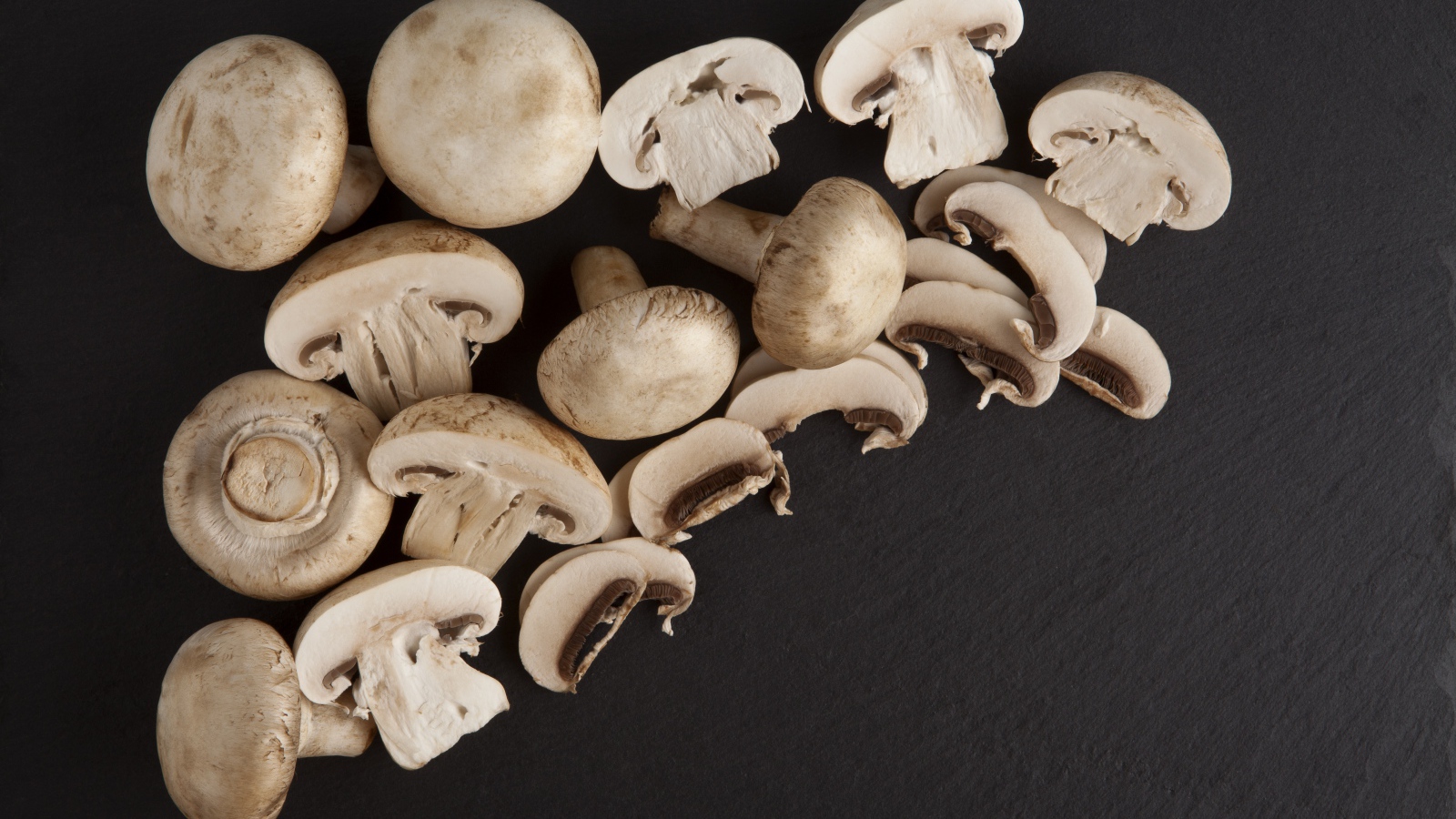 Свежие нарезанные шампиньоны на сером фоне