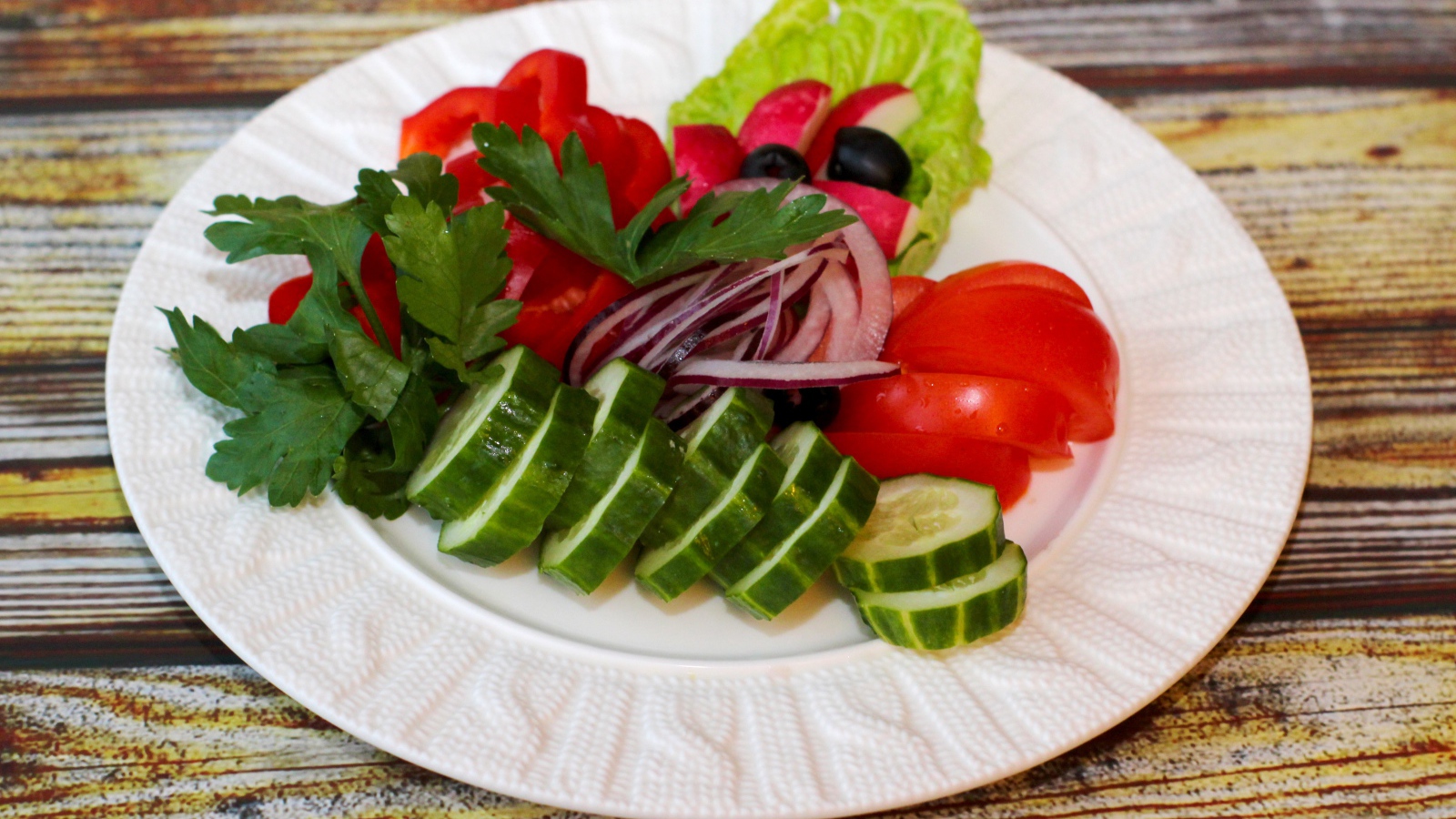 Свежие овощи на белой тарелке на деревянном фоне