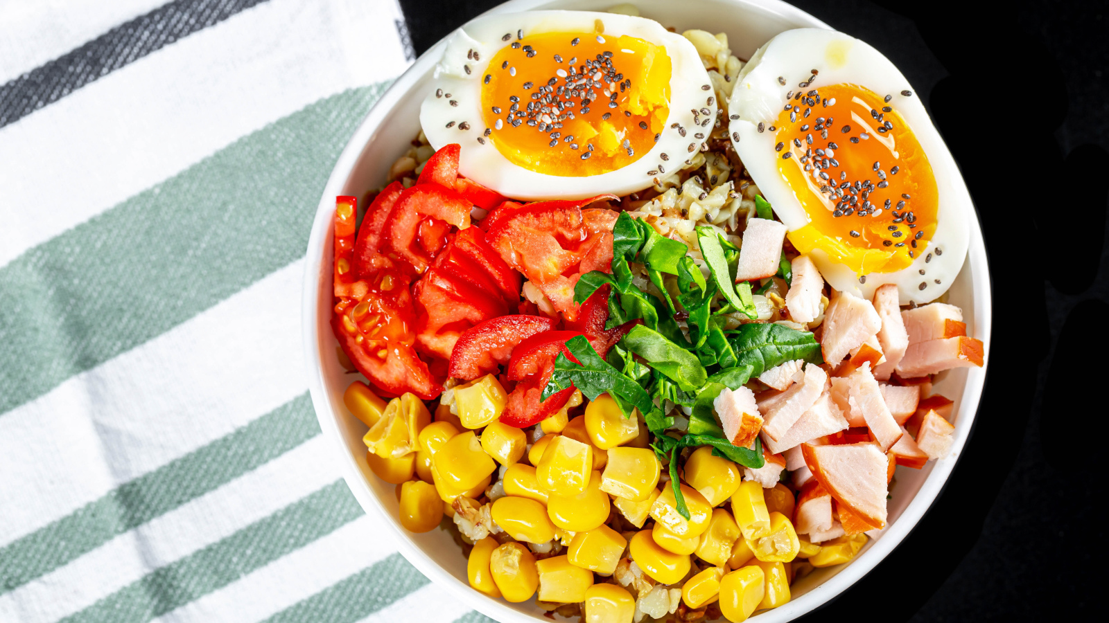 Каша в тарелке с помидорами, кукурузой, ветчиной и яйцом