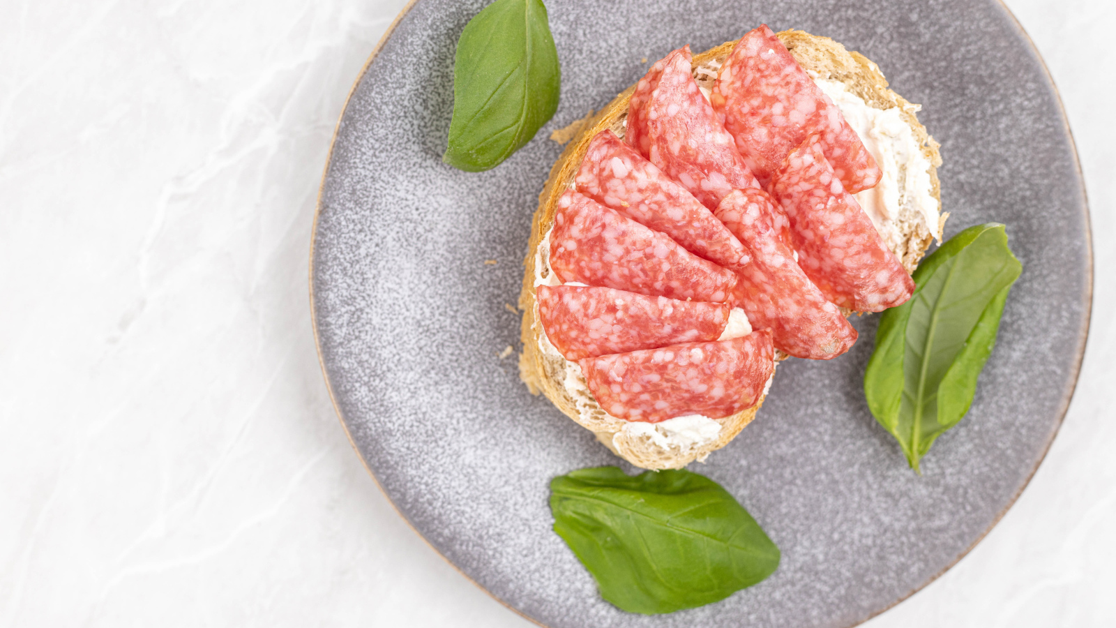 Бутерброд с маслом и колбасой на тарелке