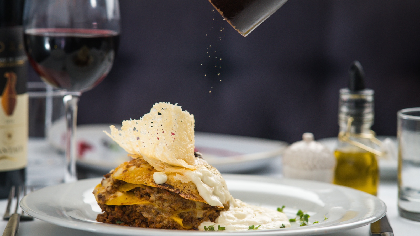 Кусок лазаньи посыпают перцем 