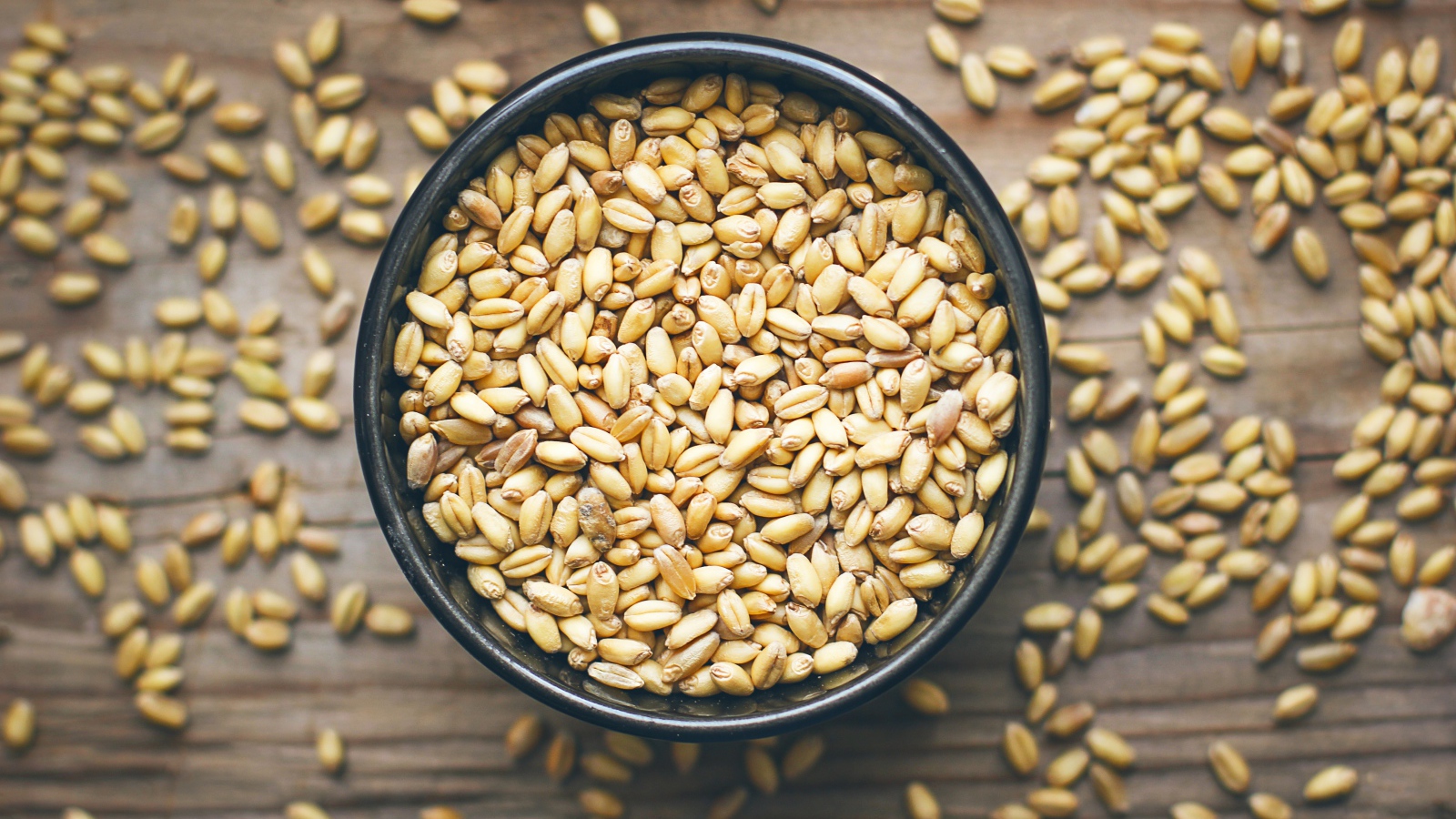 Зерна пшеницы в черной кружке на столе 