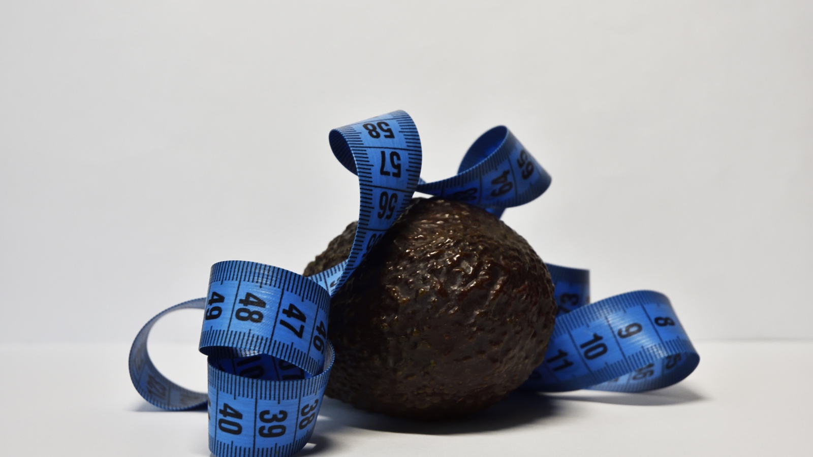 Авокадо с сантиметром на сером фоне