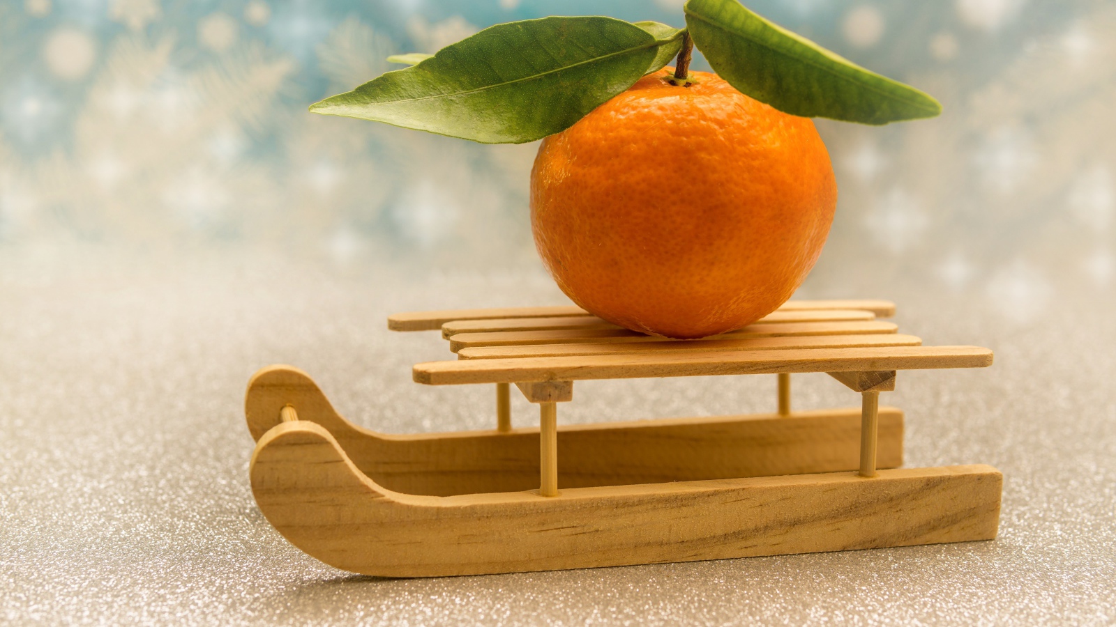 Большой оранжевый мандарин на маленьких санках