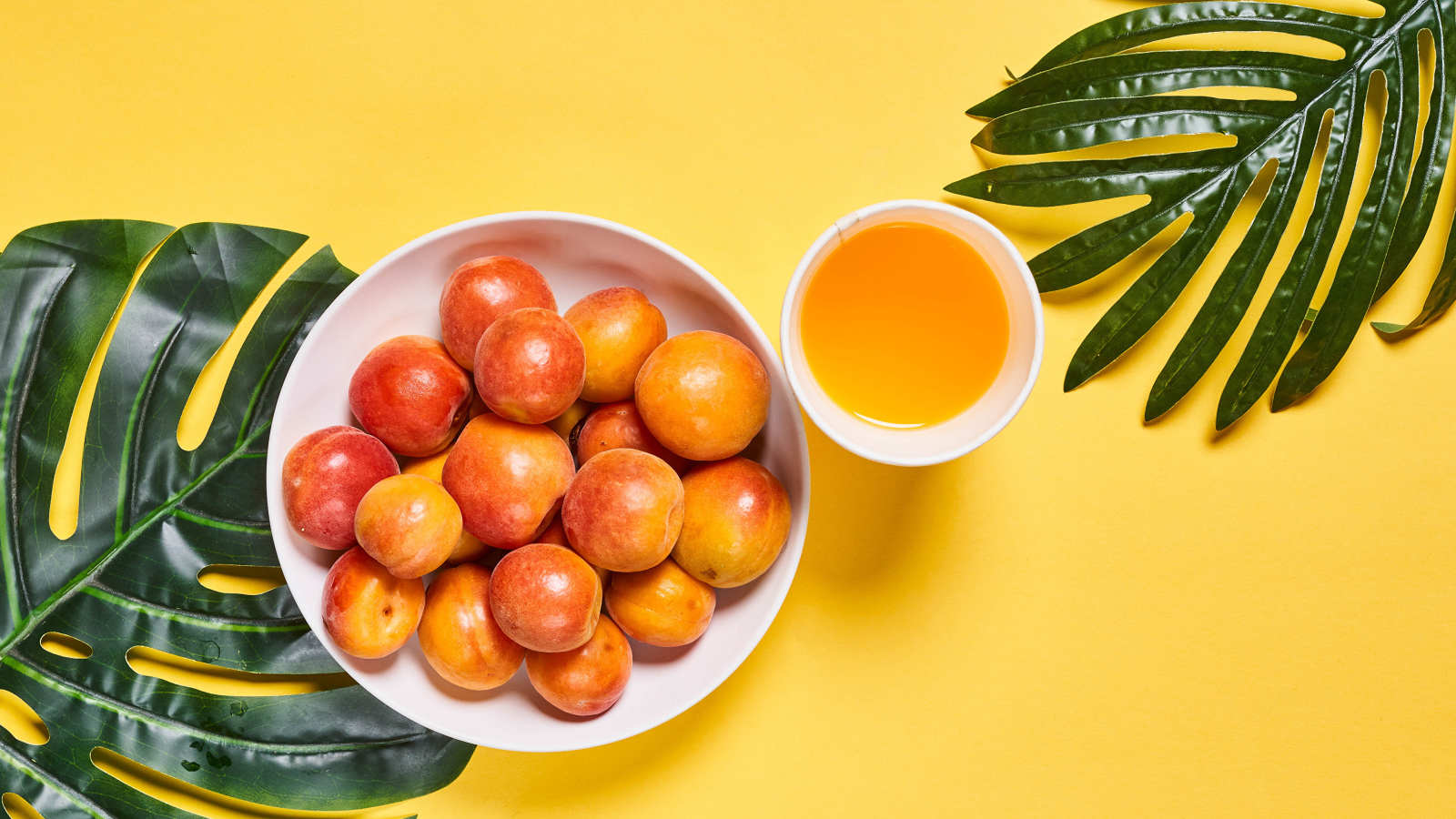 Вкусные спелые абрикосы с зелеными листьями на желтом фоне