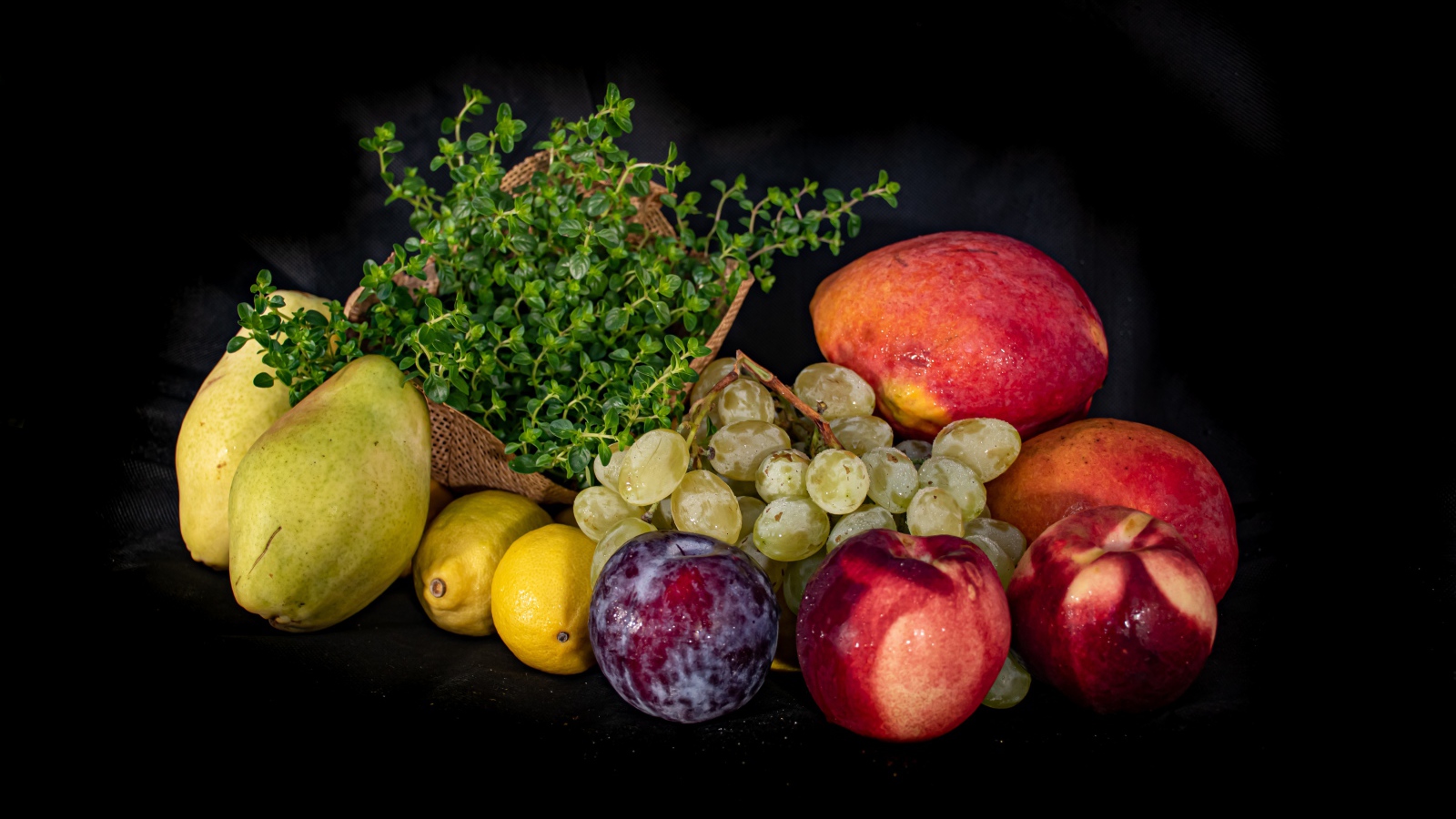 Свежие фрукты с зеленью на черном фоне 