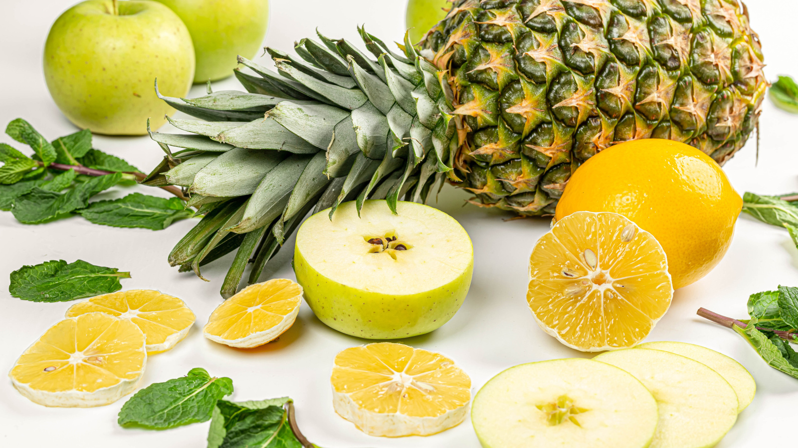 Зеленые яблоки на белом фоне с ананасом и лимоном