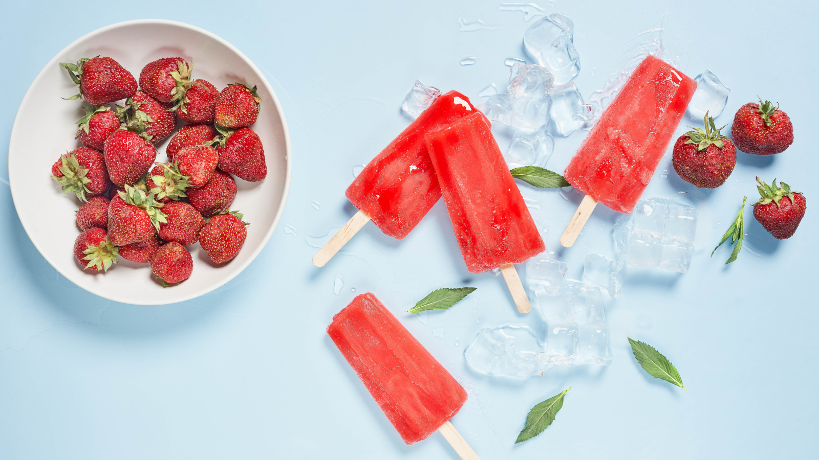 Мороженое со льдом и ягодами клубники на голубом фоне 