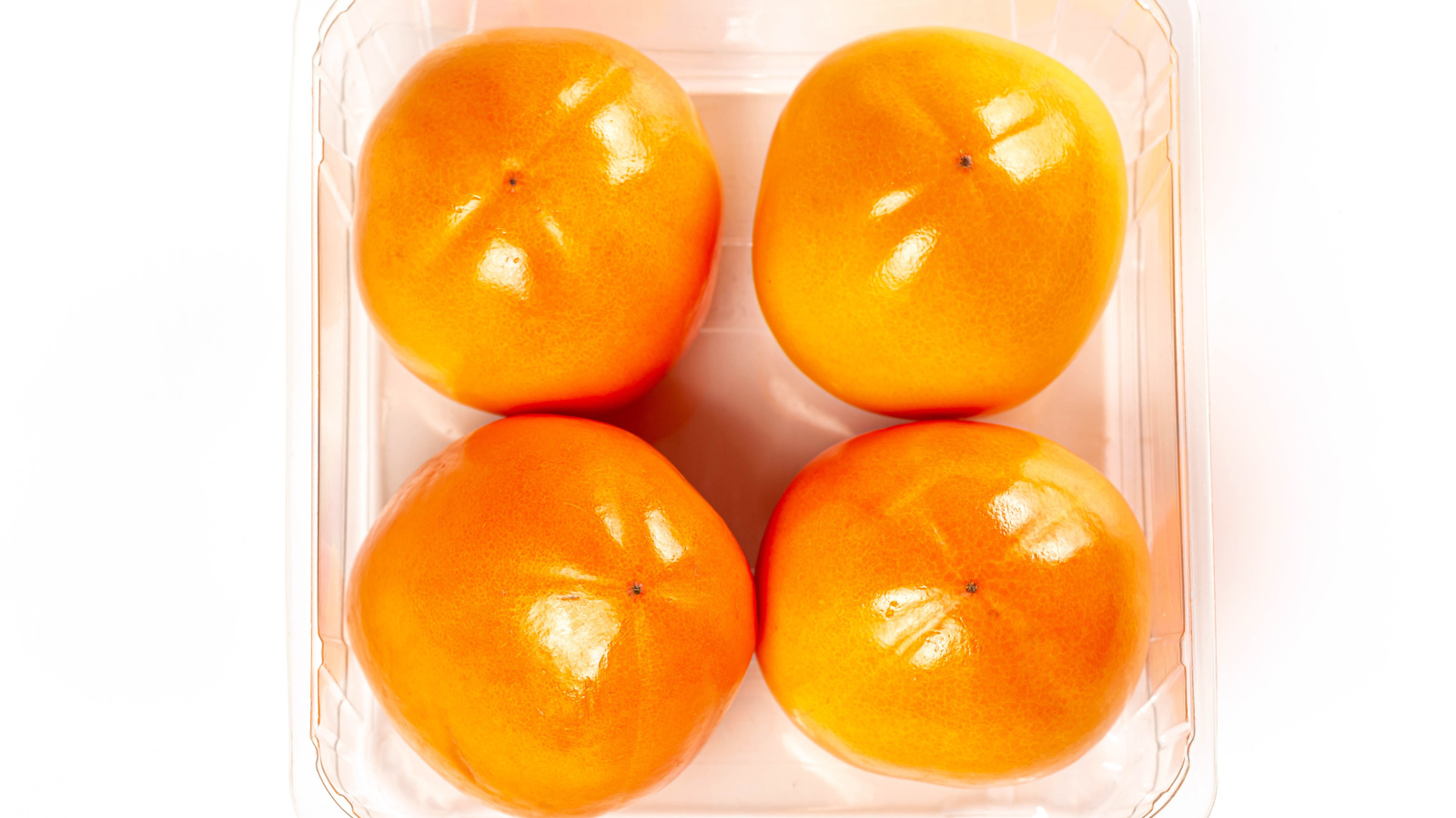 Спелая хурма с лотке на белом фоне