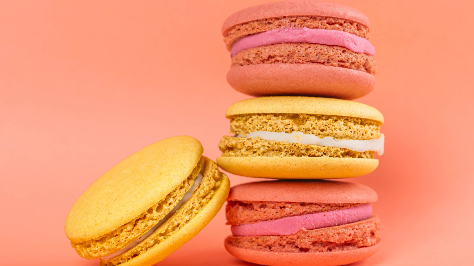 Разноцветный десерт макарон на розовом фоне