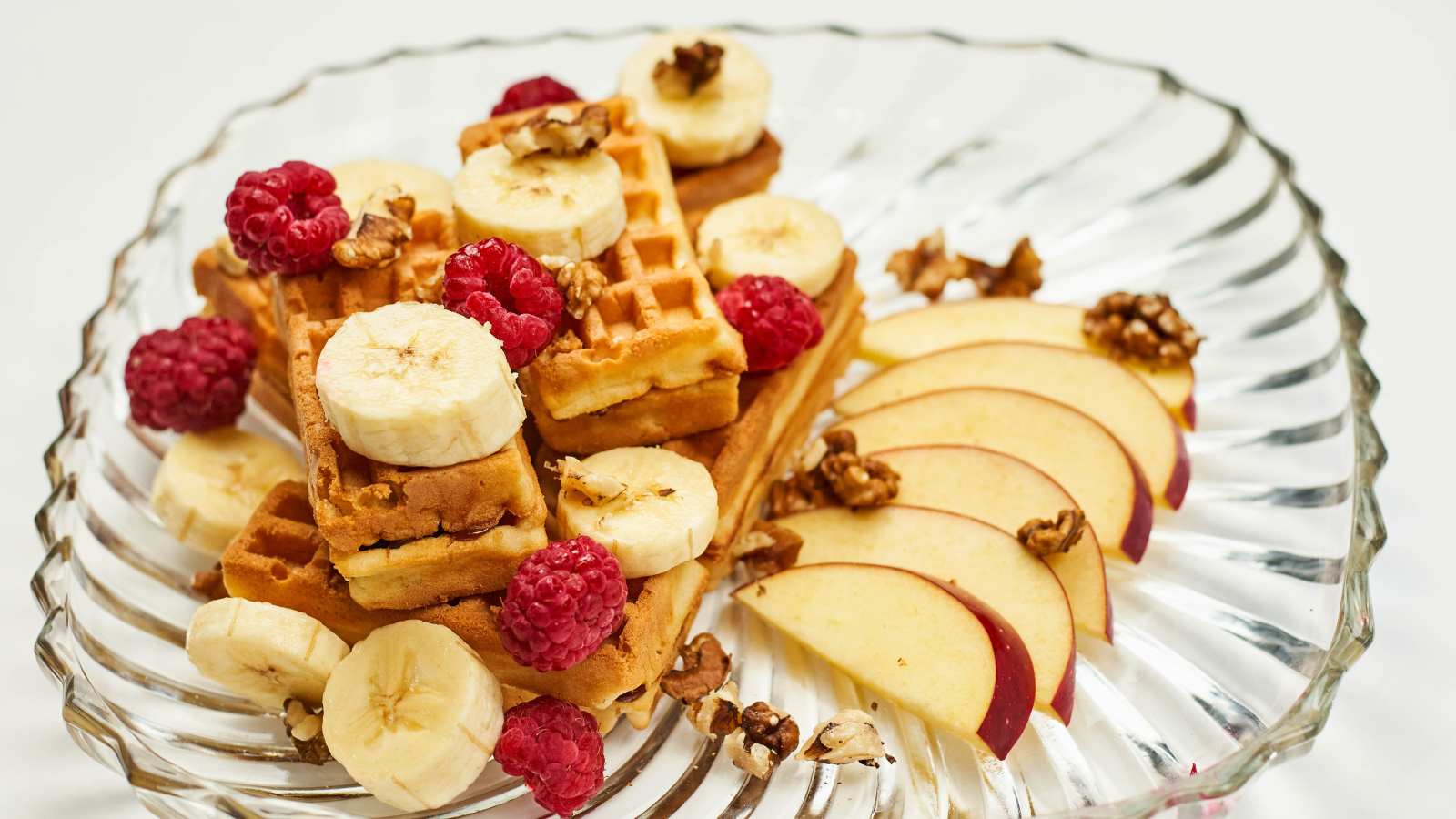 Сладкие вафли на тарелке с бананом, малиной и яблоком