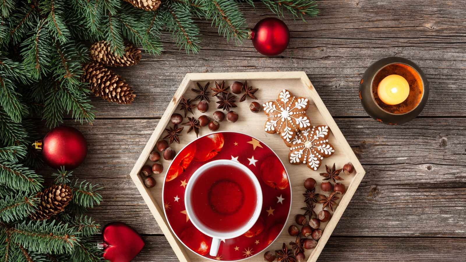 Чашка чая с печеньем и орехами на столе с еловой веткой