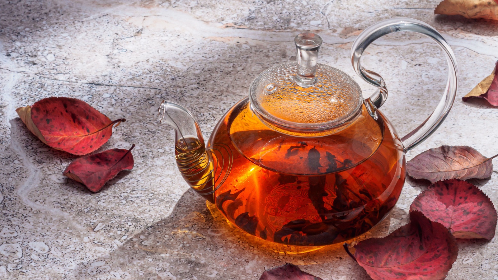 Стеклянный чайник на столе с листьями