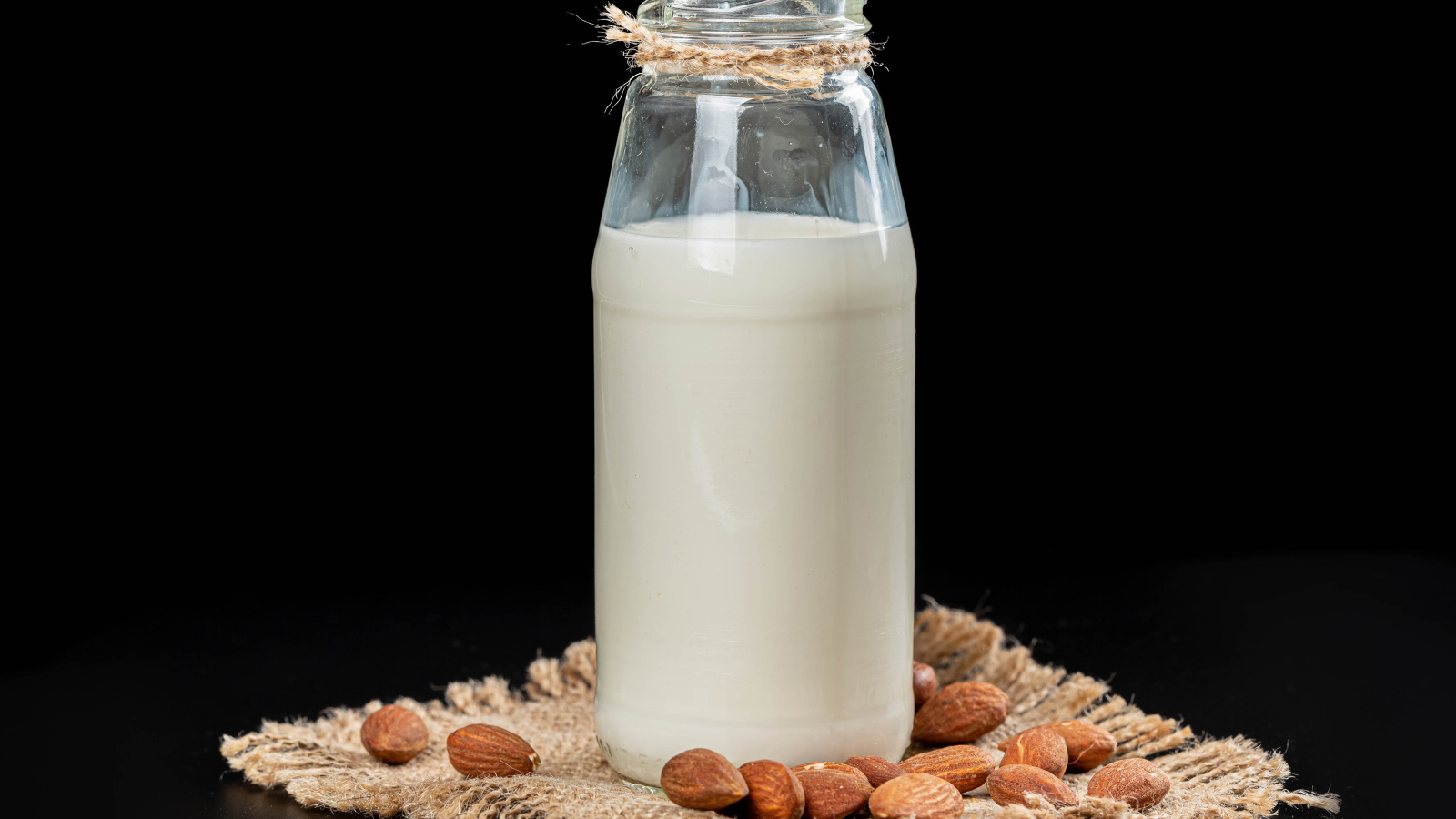Молоко с миндалем на черном фоне