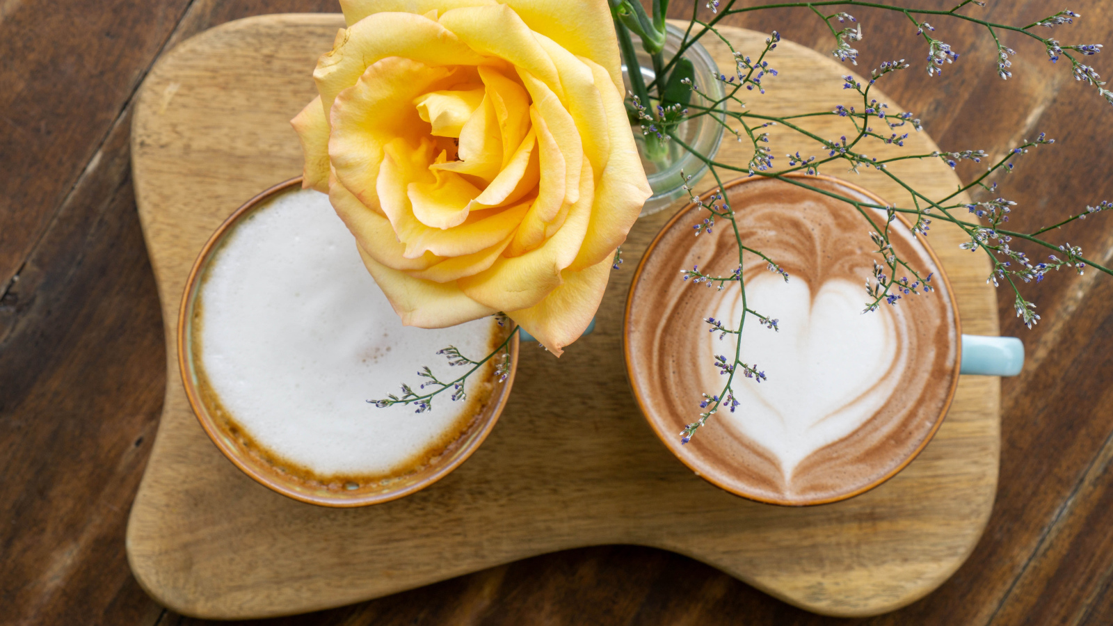 Две чашки капучино на столе с розой