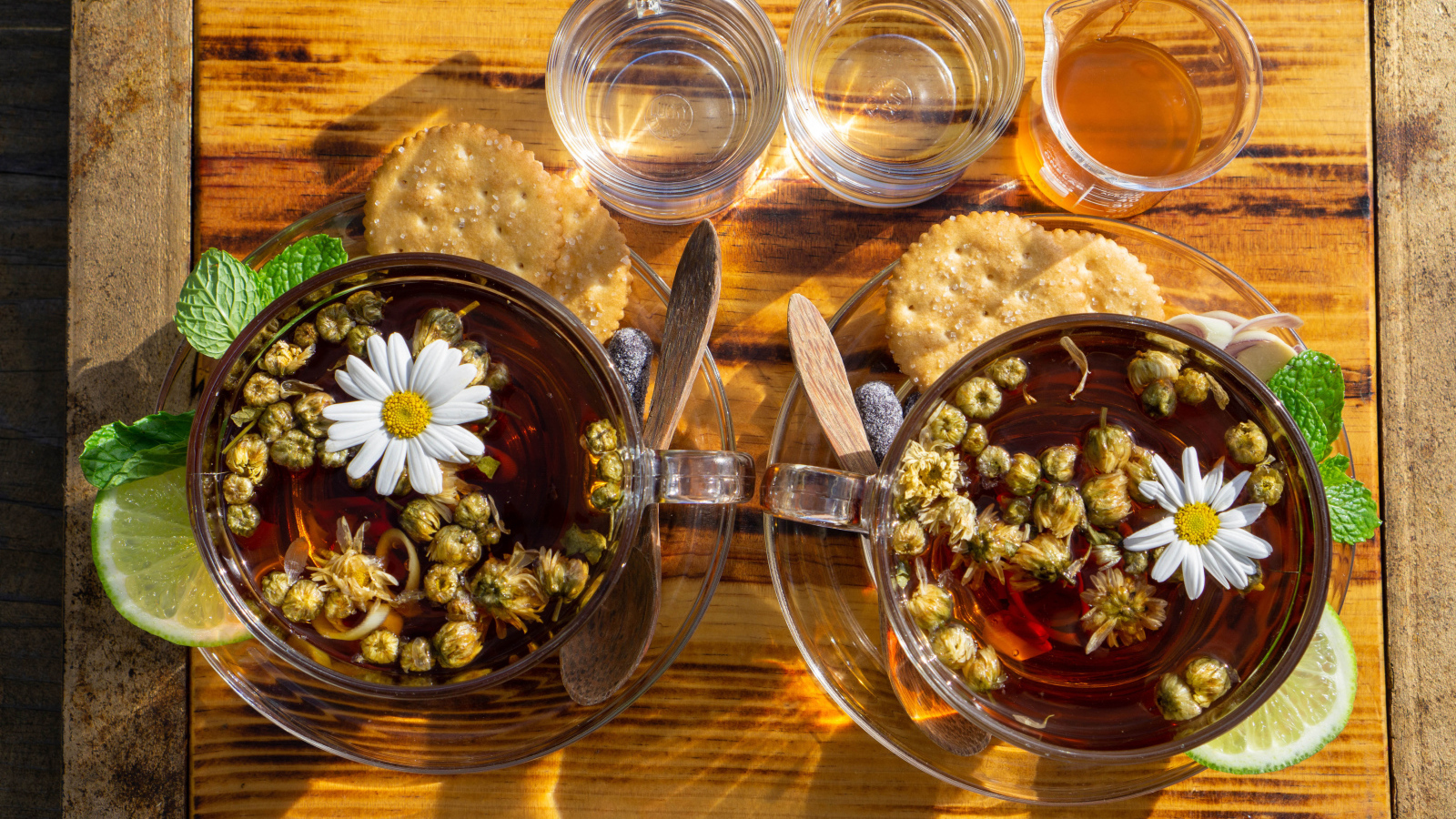 Две чашки чая с ромашкой на столе с медом