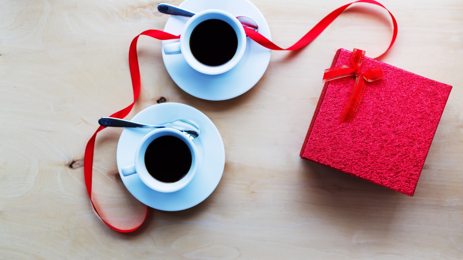Две чашки кофе на столе с подарком