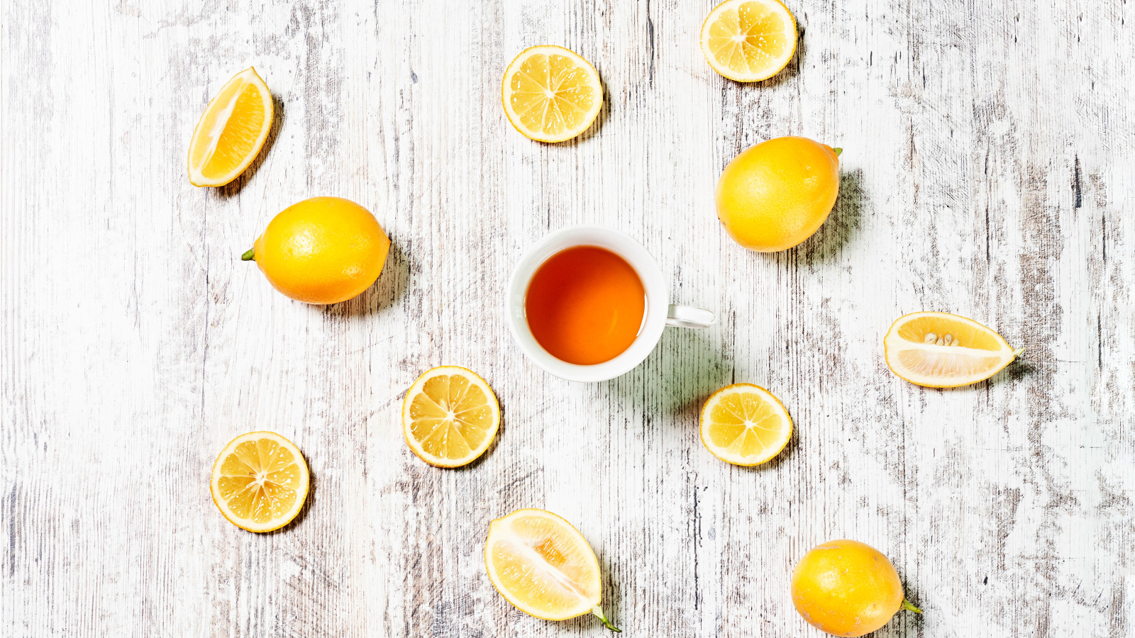 Желтые лимоны с чаем на белом столе 