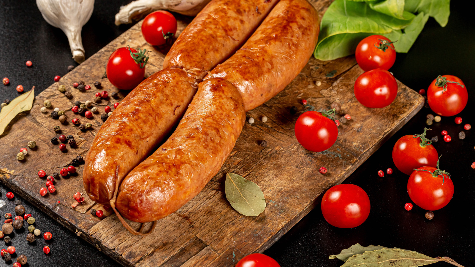 Мясные колбаски на доске с овощами