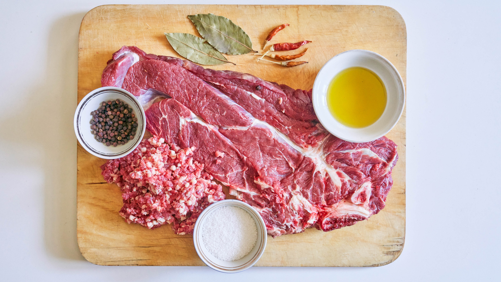 Кусок мяса со специями и оливковым маслом на доске 