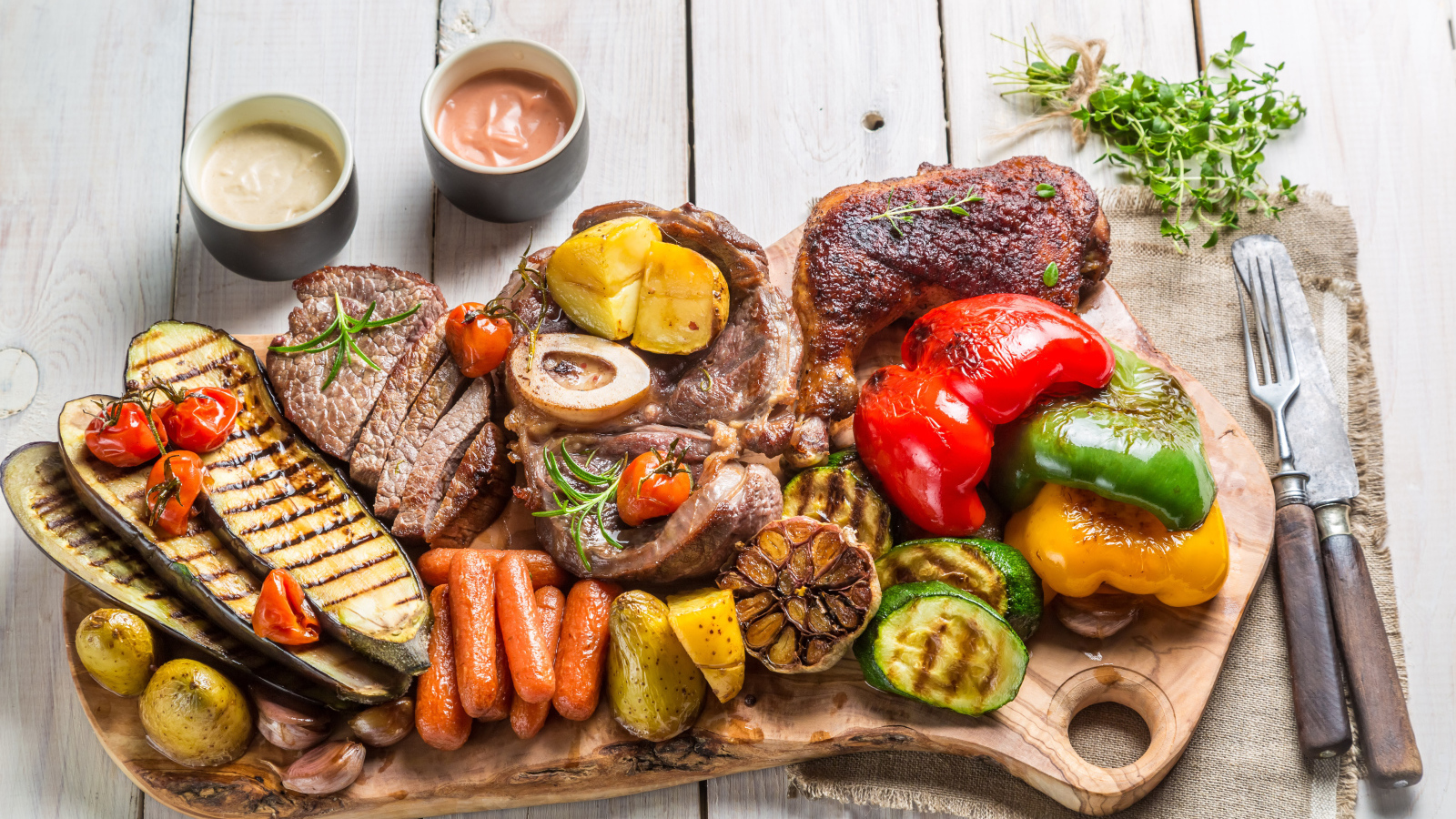 Pieces of baked meat on a board with vegetables