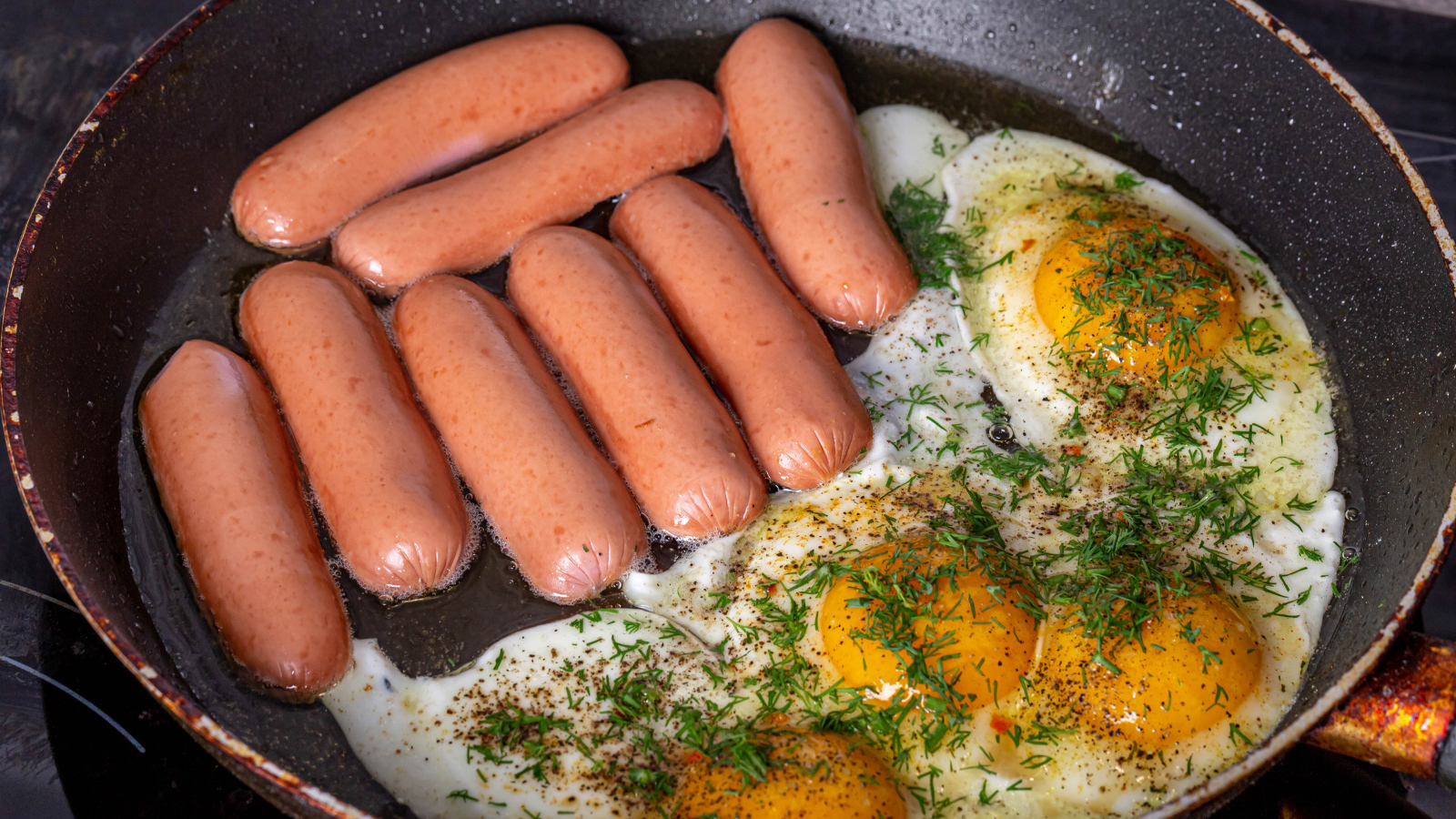 Сосиски с яичницей на сковороде