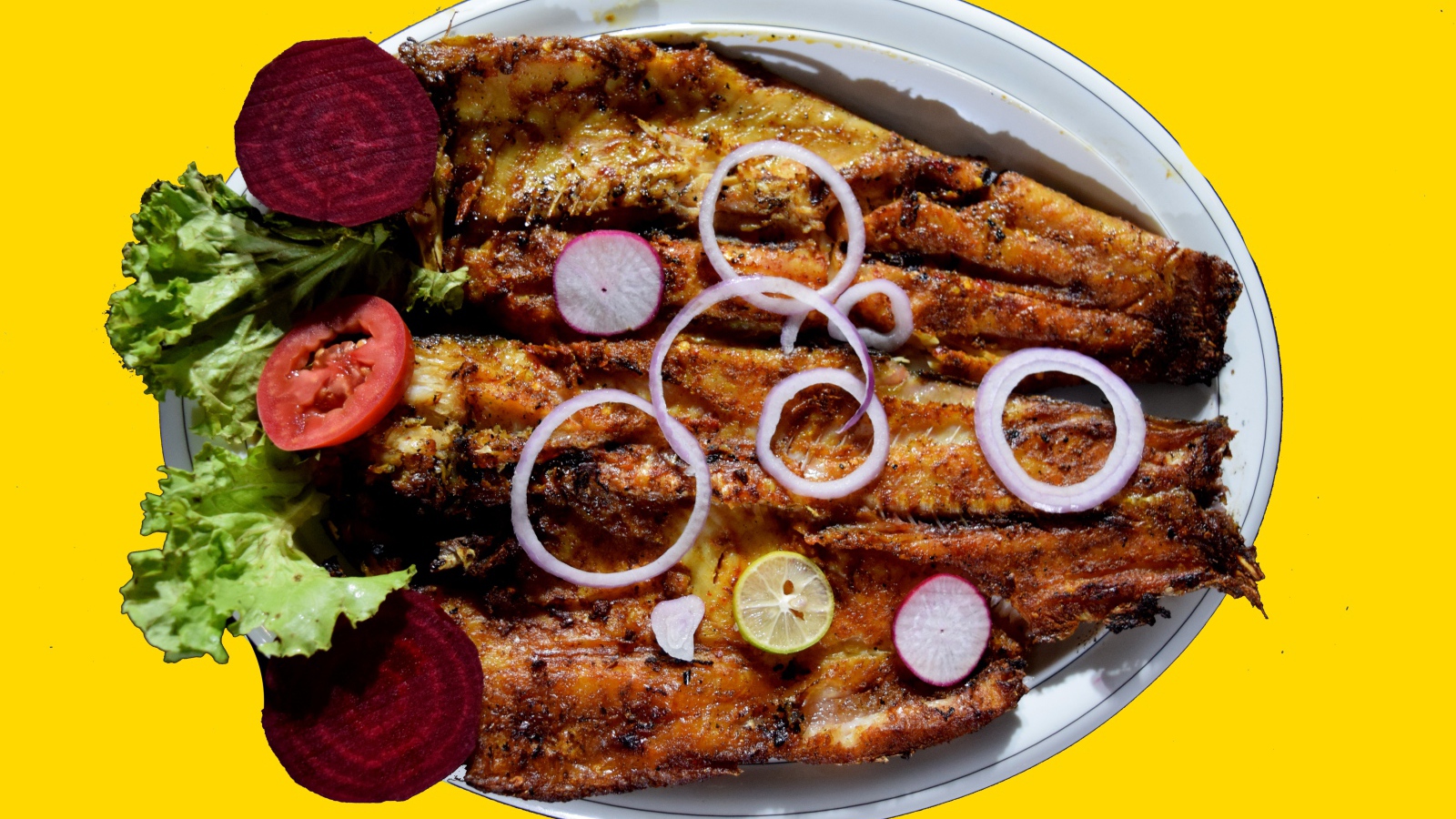 Жареная рыба с листьями салата, помидорами и свеклой на желтом фоне