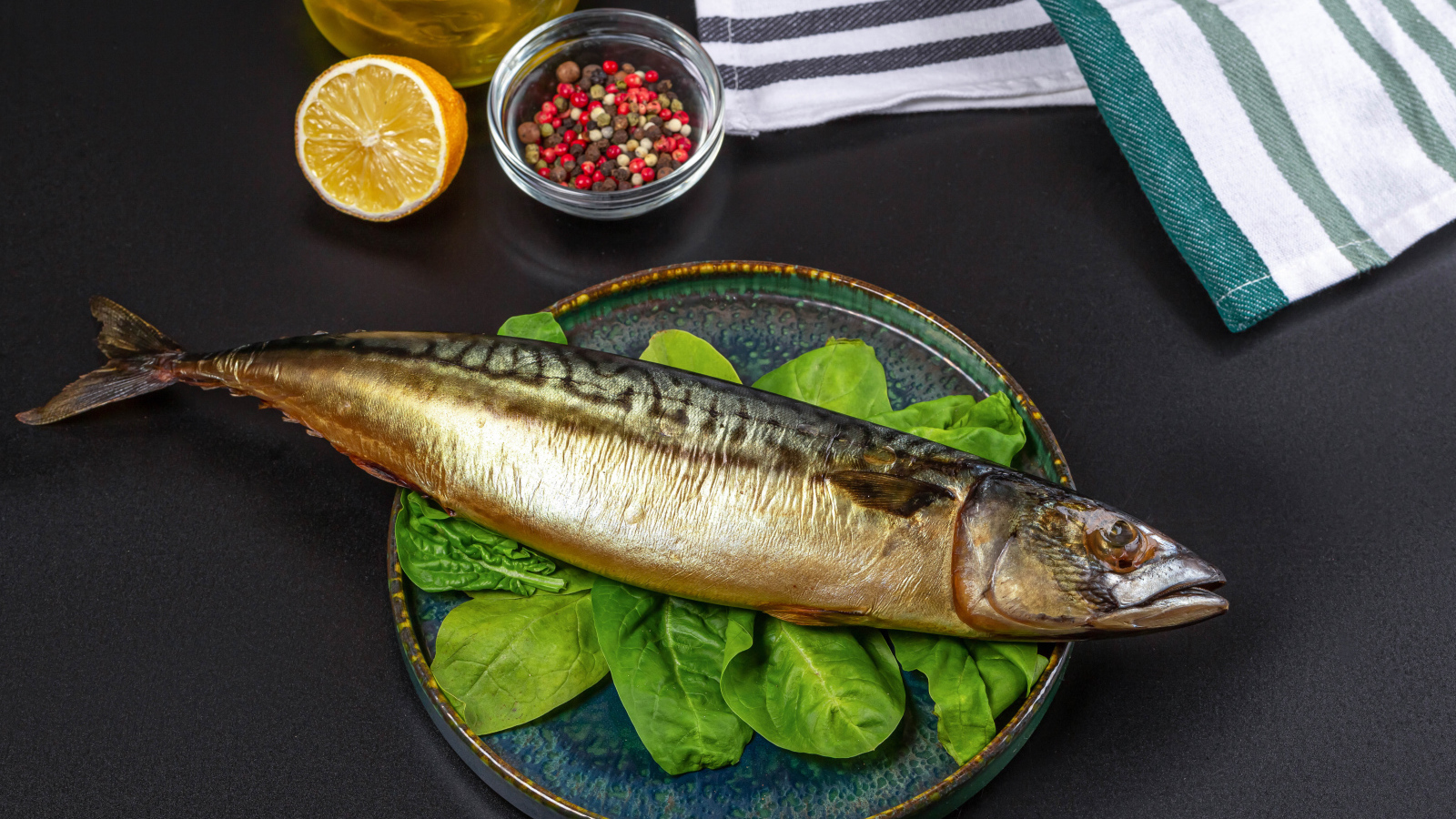 Большая копченая скумбрия на тарелке с базиликом