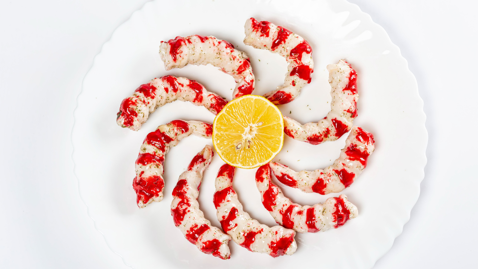 Тигровые креветки на тарелке с лимоном на белом фоне 