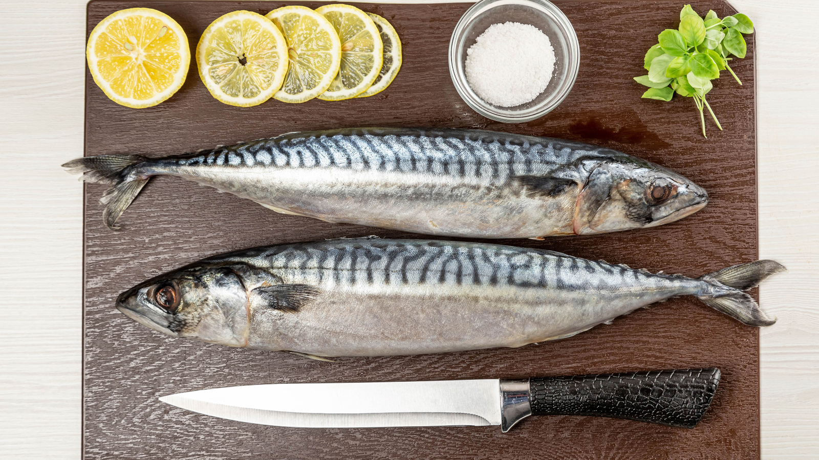 Две свежие скумбрии на доске с лимоном 