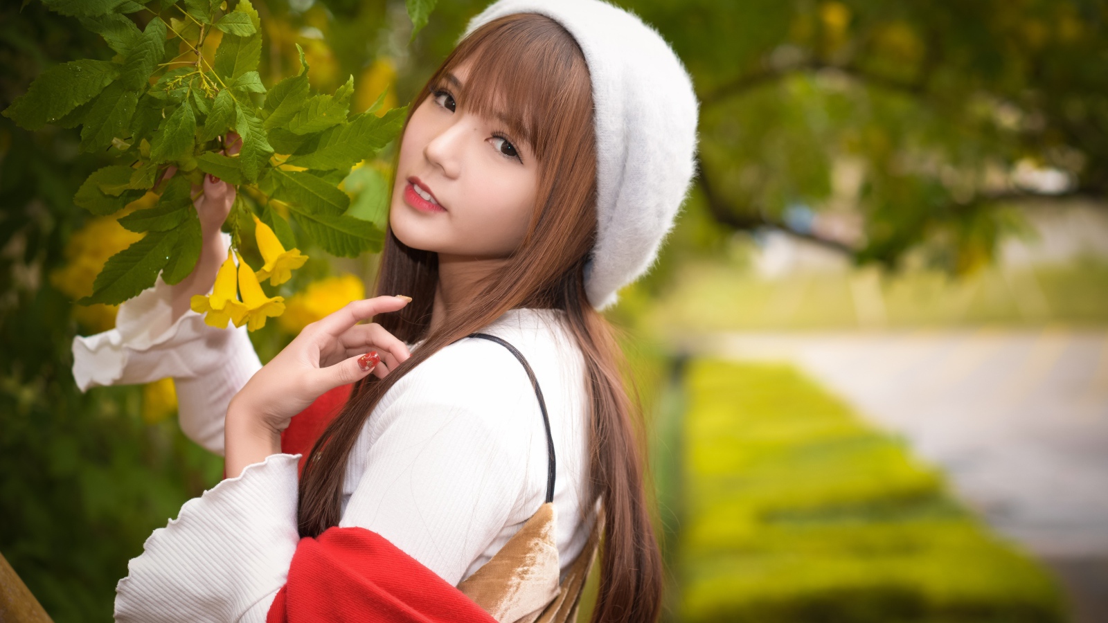 Девушка в берете стоит у куста с желтыми цветами