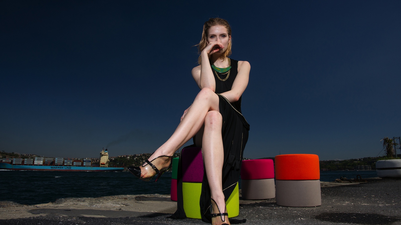 Девушка в черном платье сидит у воды