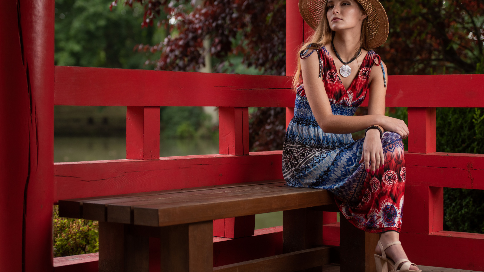 Молодая девушка в платье сидит на лавке 